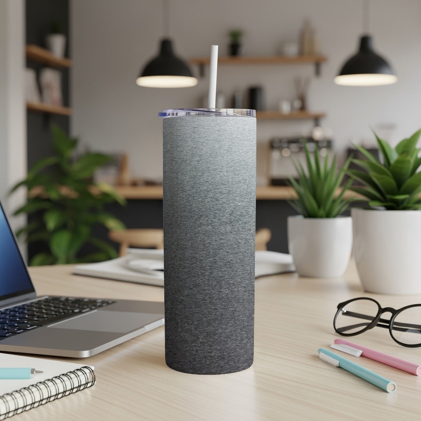 Tall, grey ombre tumbler with straw on a desk next to a laptop.