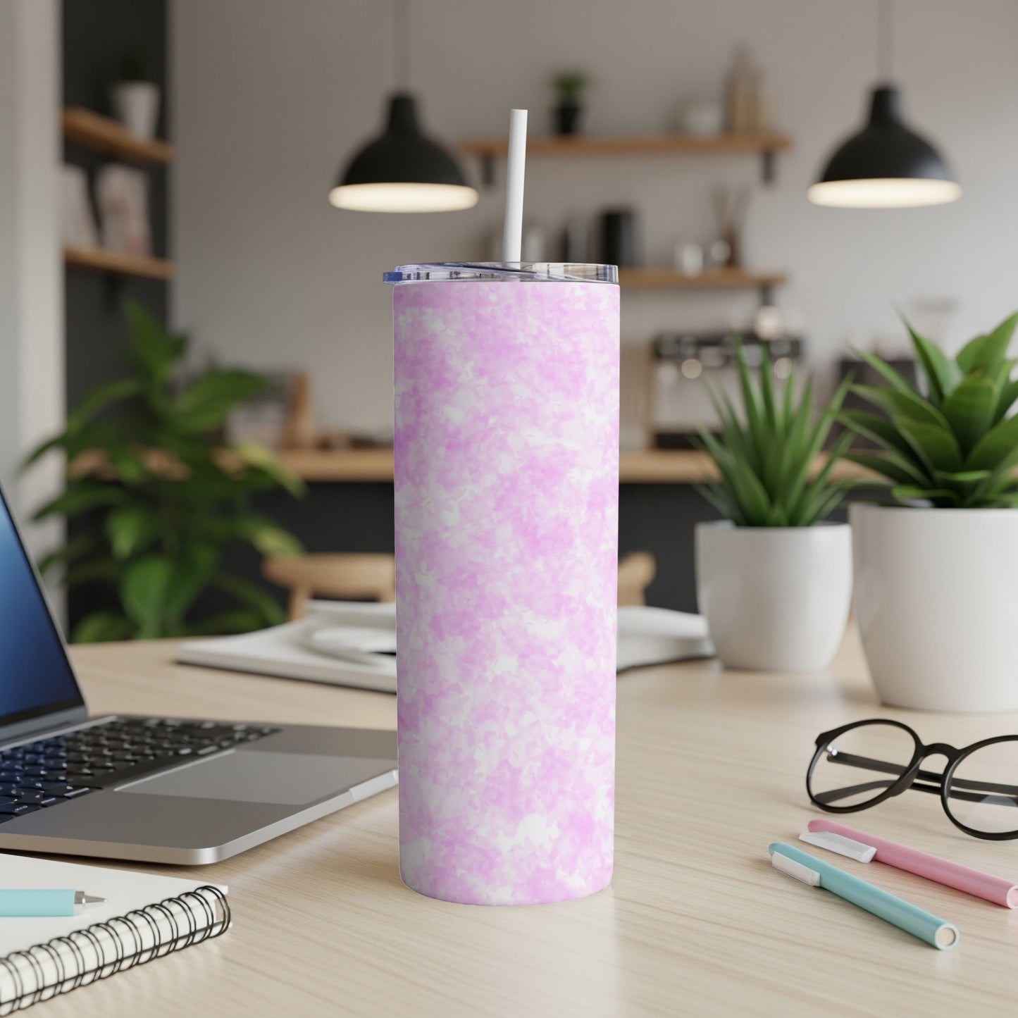 Pink and white marbled tumbler with straw on a desk.