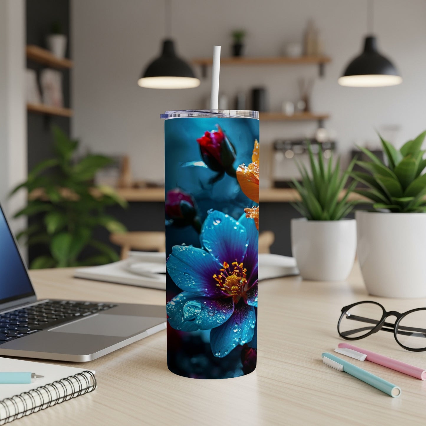 Blue and orange flower tumbler with straw on desk.