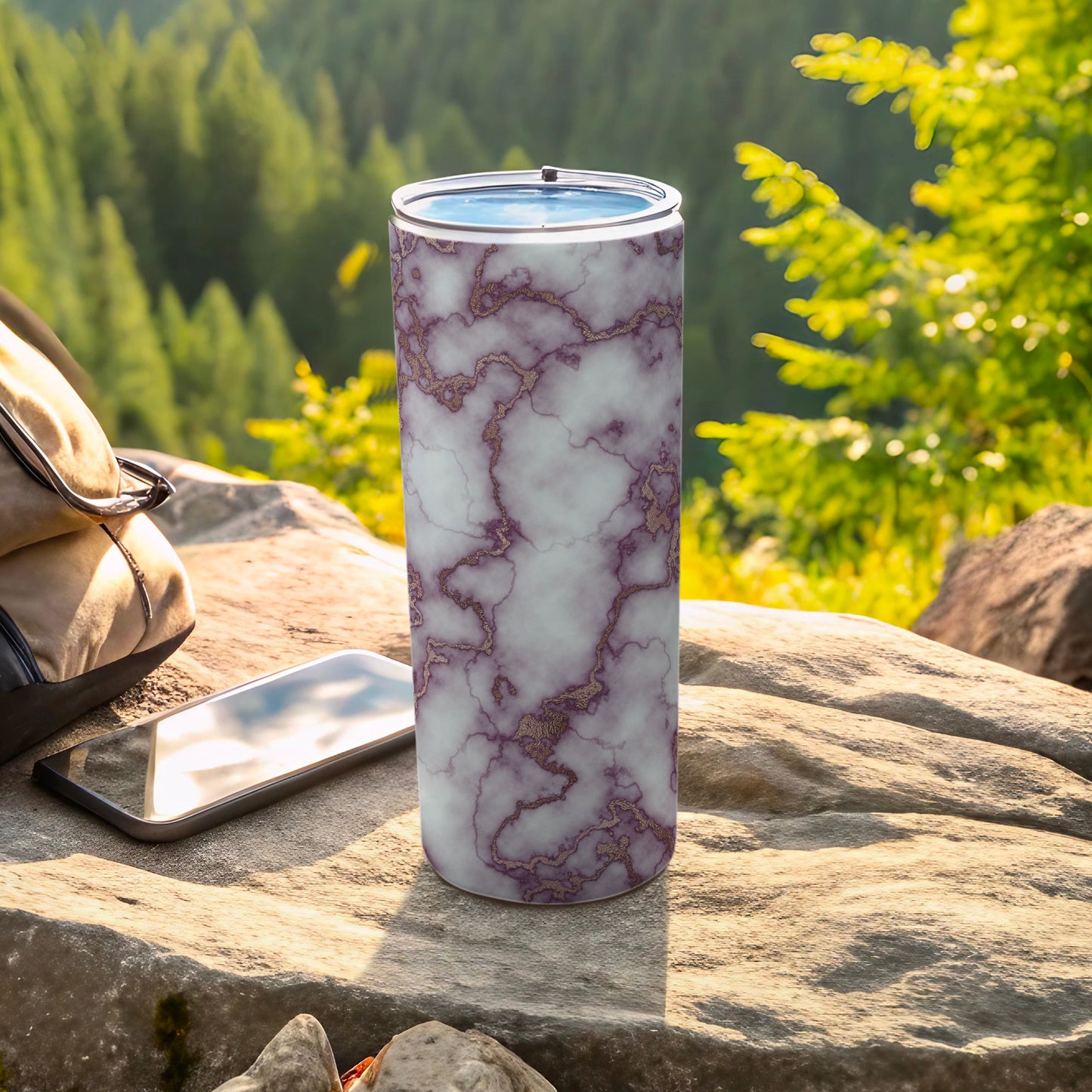 Purple marble tumbler with gold veins, next to phone and backpack outdoors.