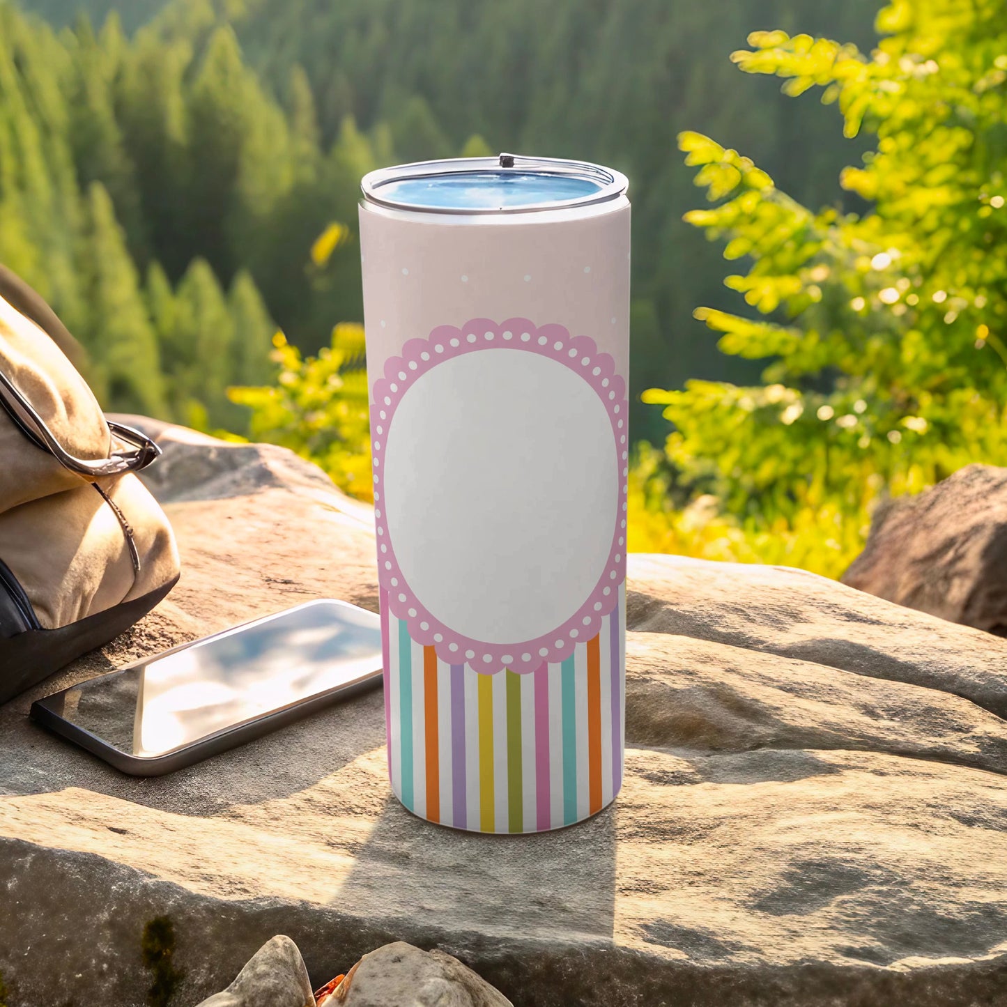 Pink patterned tumbler with a blank white circle and striped base on rocks.
