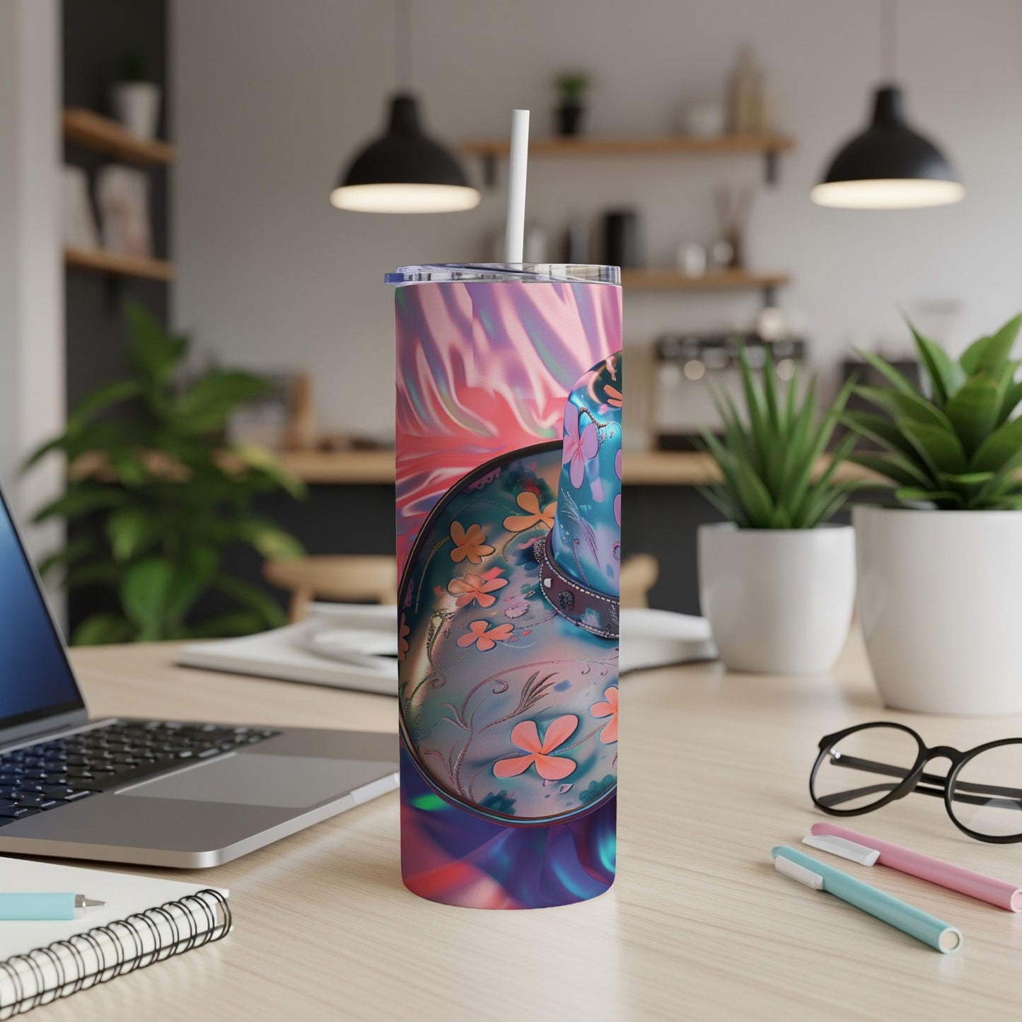 Tumbler with iridescent floral pattern and straw on a desk.