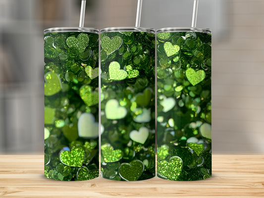 Three green glitter heart tumblers with straws on a wooden surface.