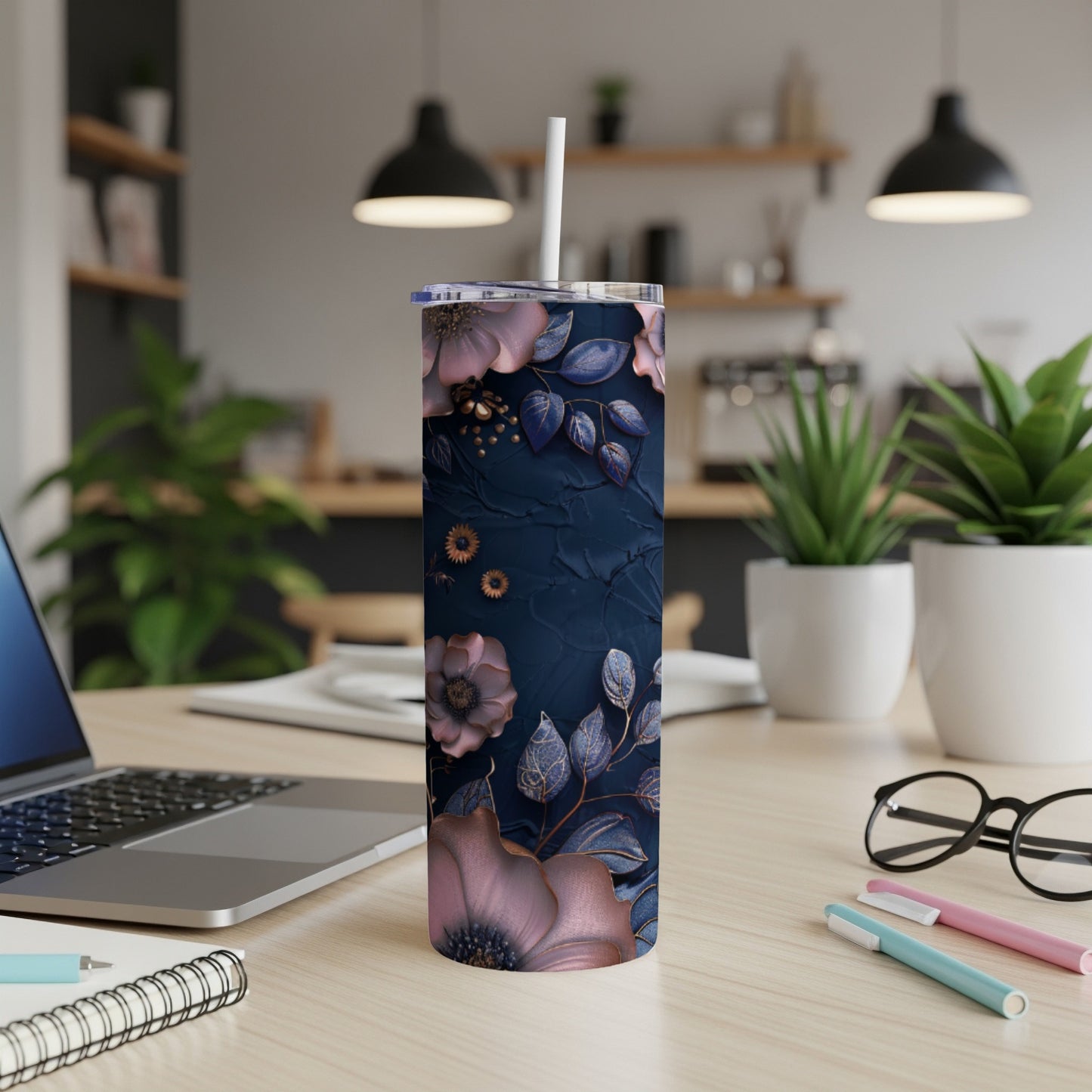 Navy blue tumbler with floral design and straw on a desk.