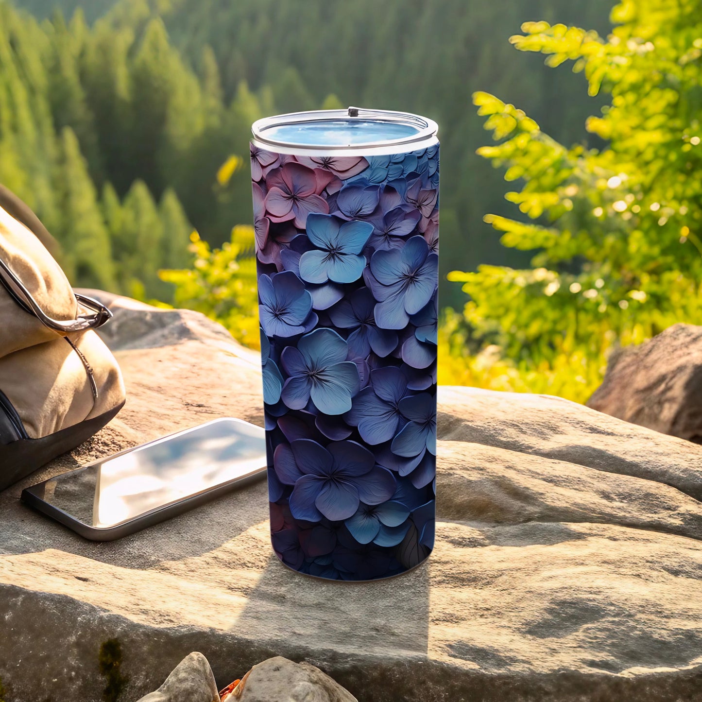 Tall tumbler with purple and blue hydrangea flower pattern on a rocky outdoor surface.