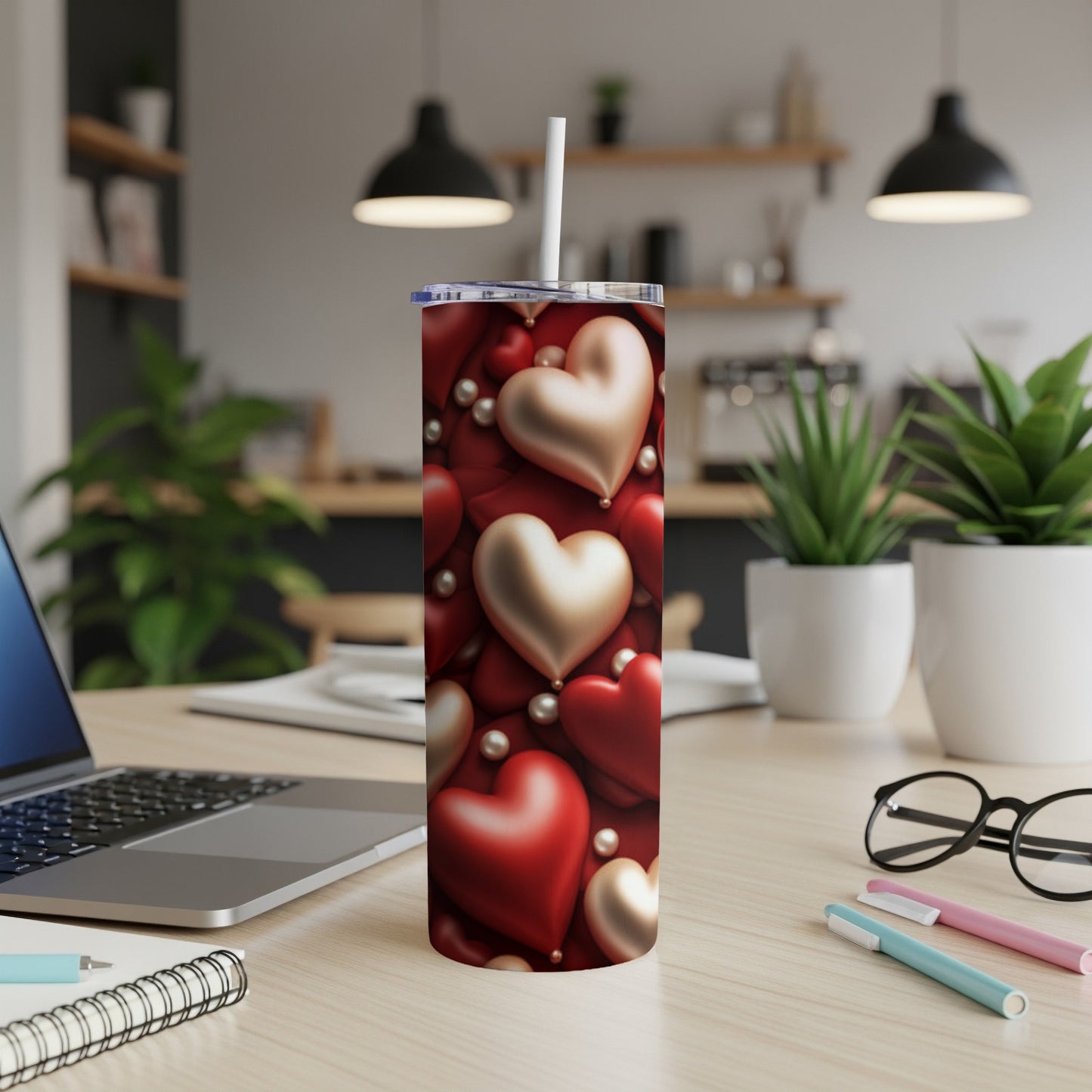 Red and gold heart pattern tumbler with white straw on desk.