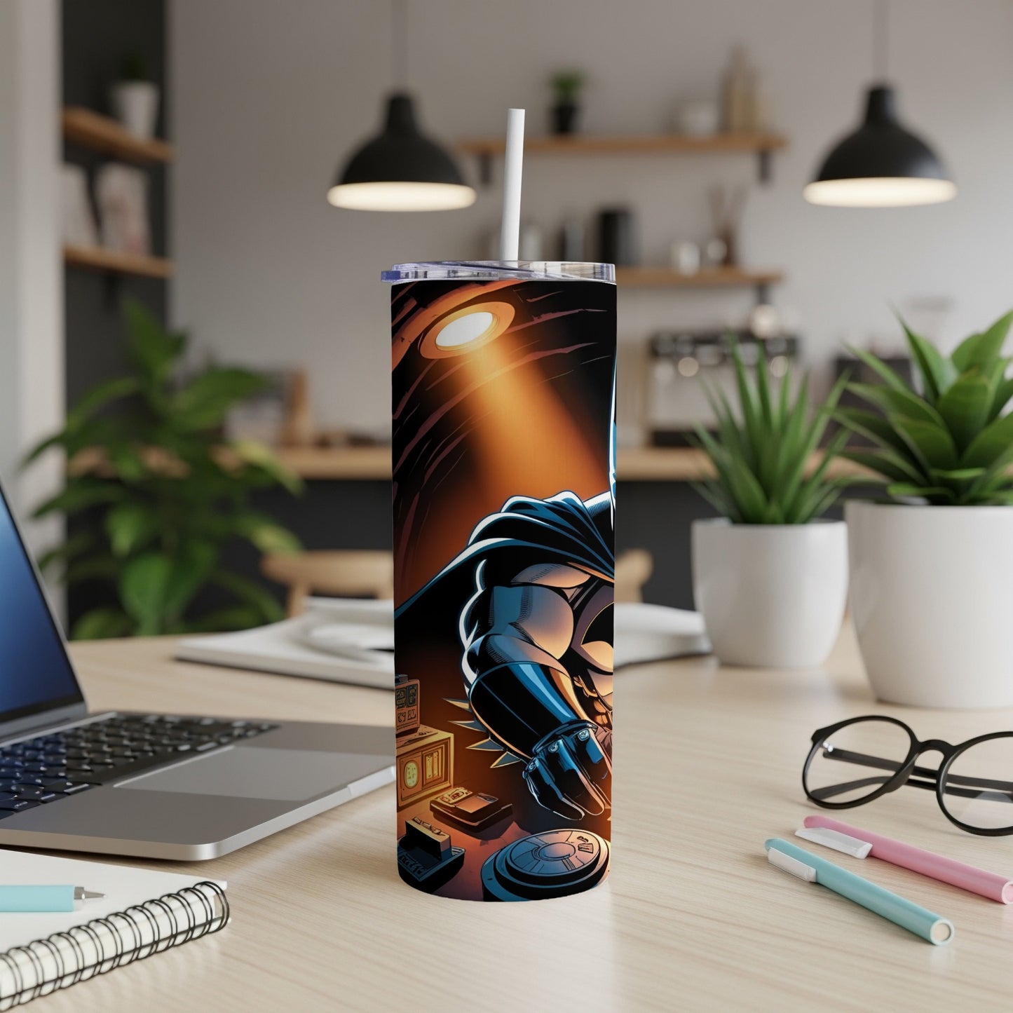 Batman tumbler with laptop and office supplies on desk.
