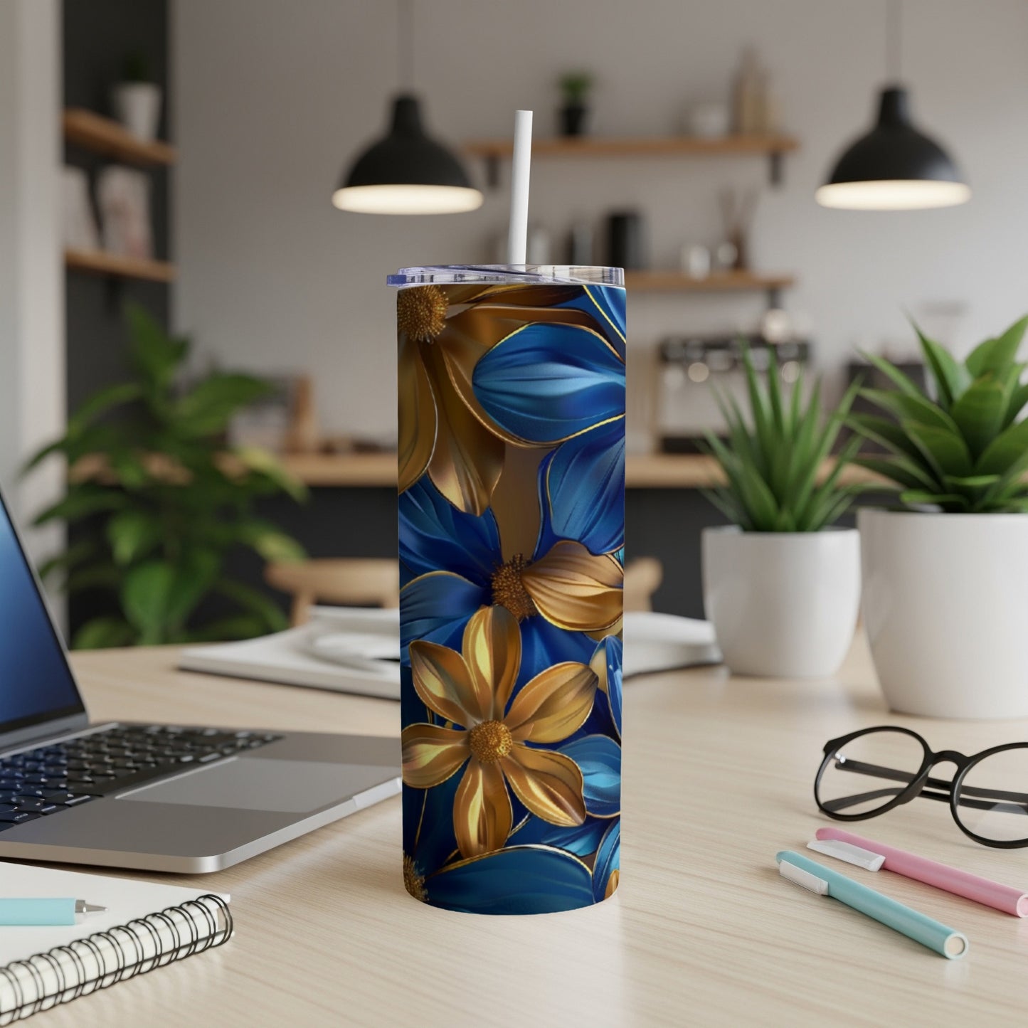 Gold and blue floral pattern on a white tumbler with a straw.