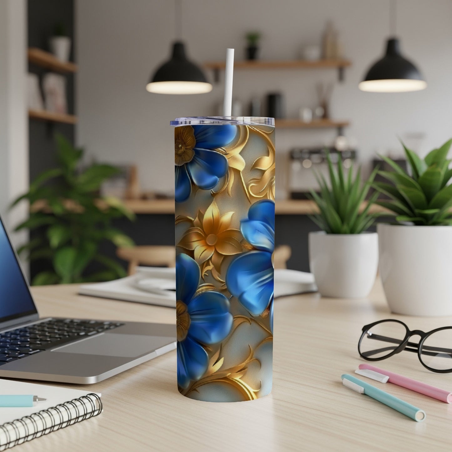 Blue floral patterned tumbler with a straw on a desk.