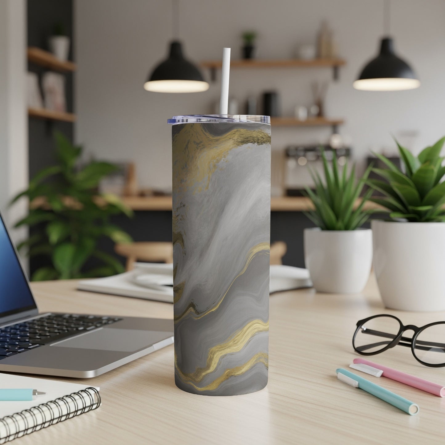 Marble and gold patterned tumbler with straw on a desk.