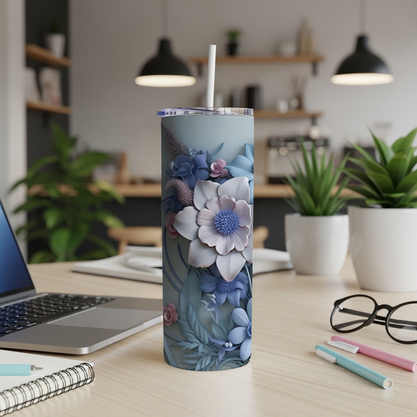 Blue floral patterned tumbler with a straw on a desk next to a laptop.
