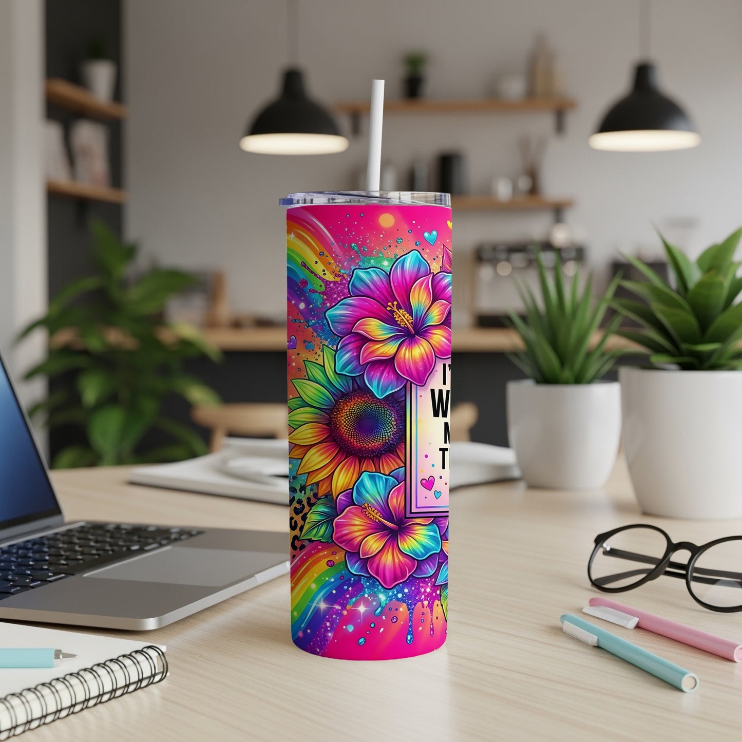 Tumbler with colorful flowers, sunflowers, and rainbow accents on a desk.