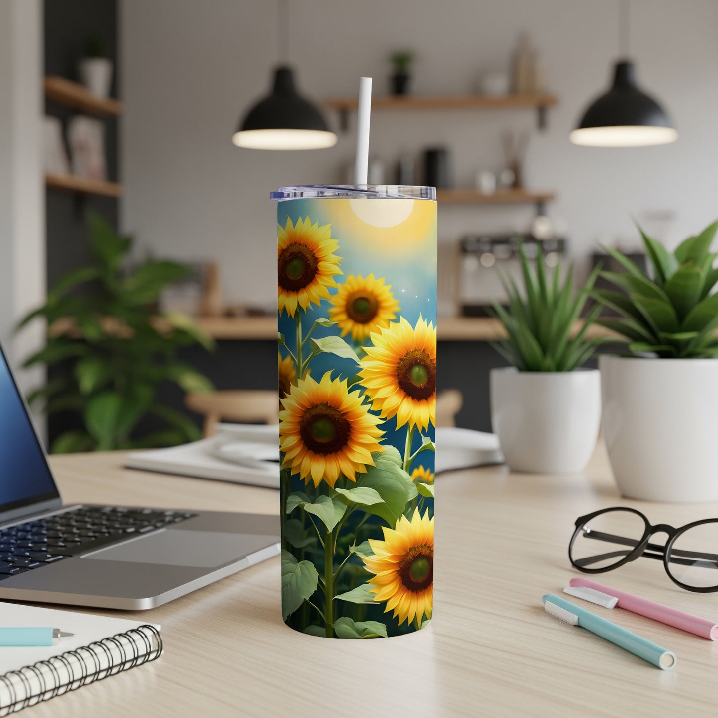 Tall tumbler with sunflowers and a blue sky background on a desk.