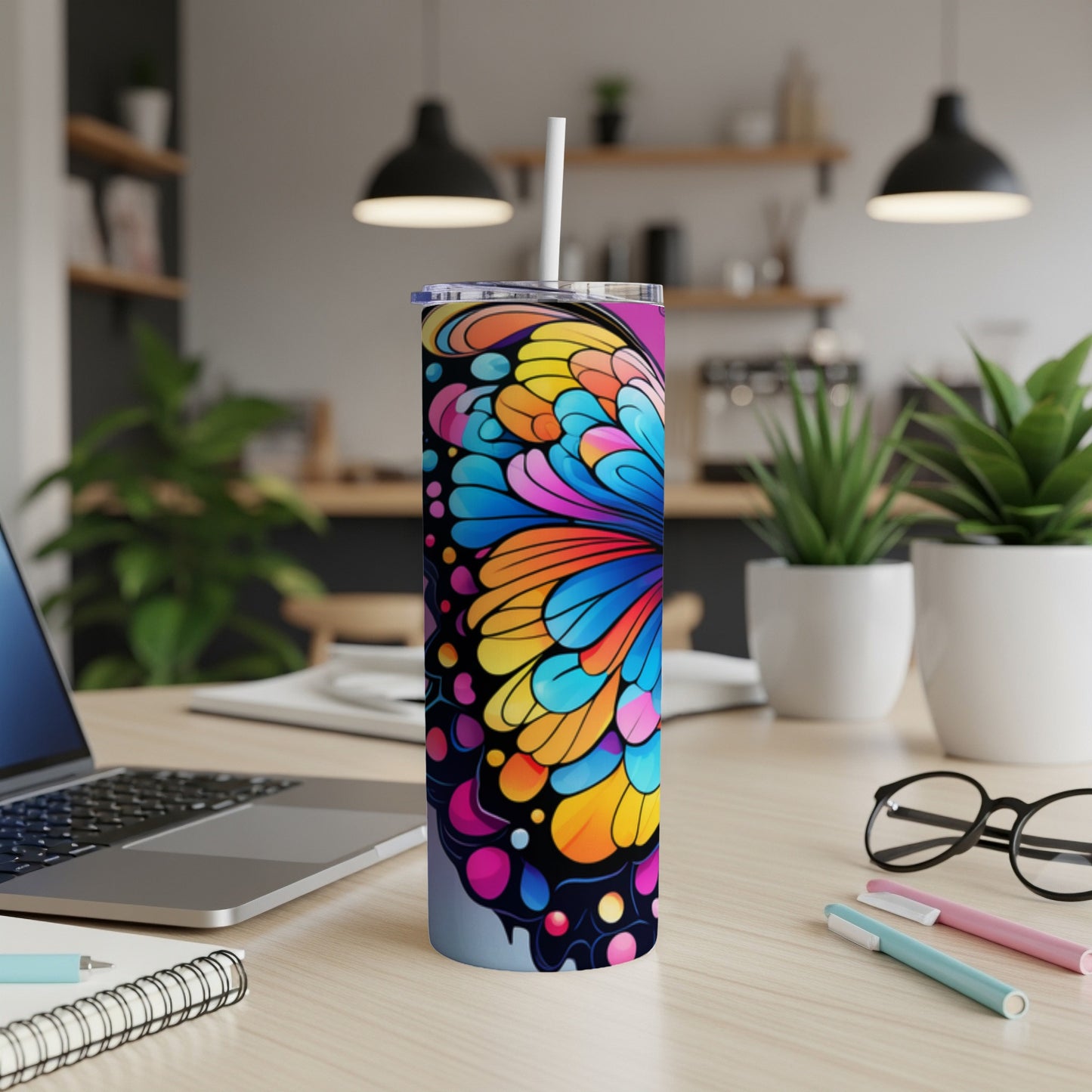 Tall tumbler with colorful abstract butterfly wing design on a desk.