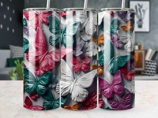 Three tumblers with colorful butterfly designs, standing on a marbled surface.