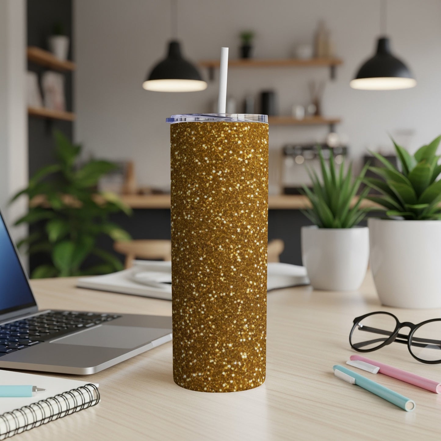 Gold glitter tumbler with white straw on a desk with laptop.