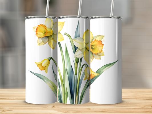 White tumblers with watercolor daffodils and green leaves on a wooden surface.