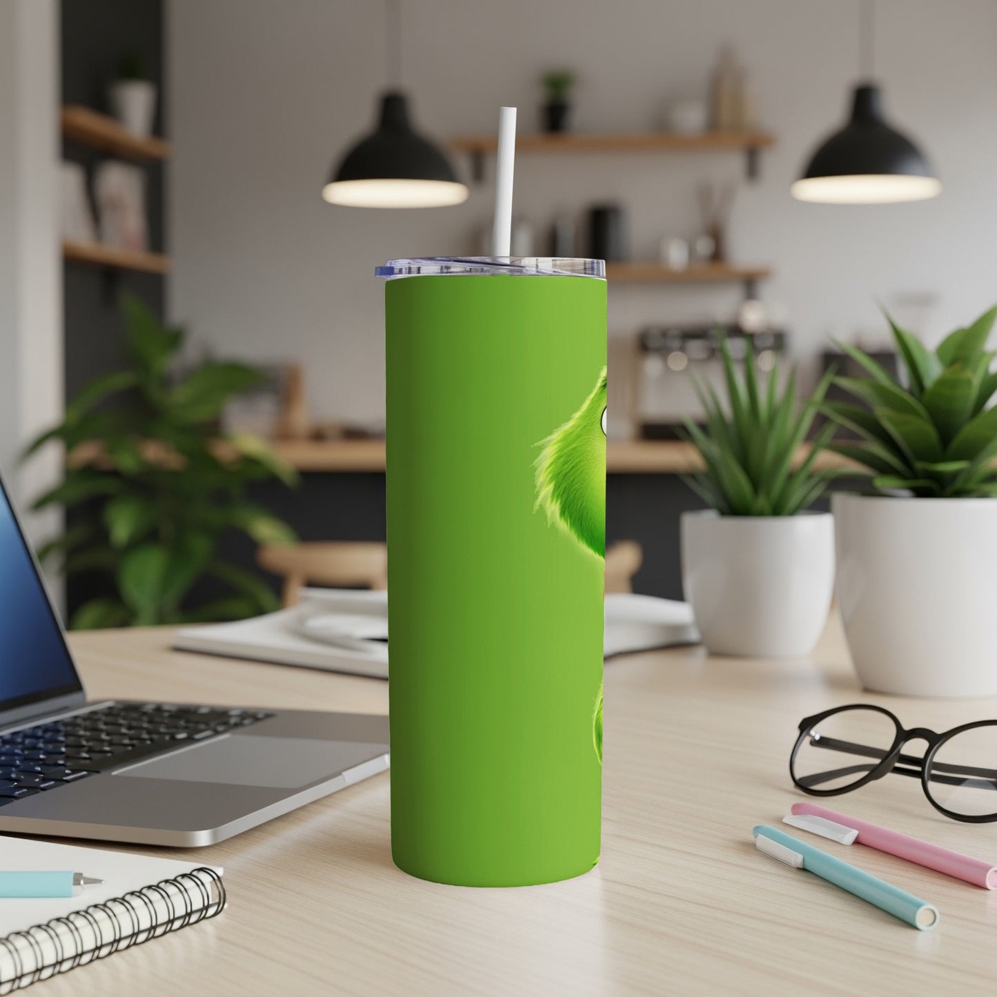 Green Grinch tumbler with a straw on a desk.