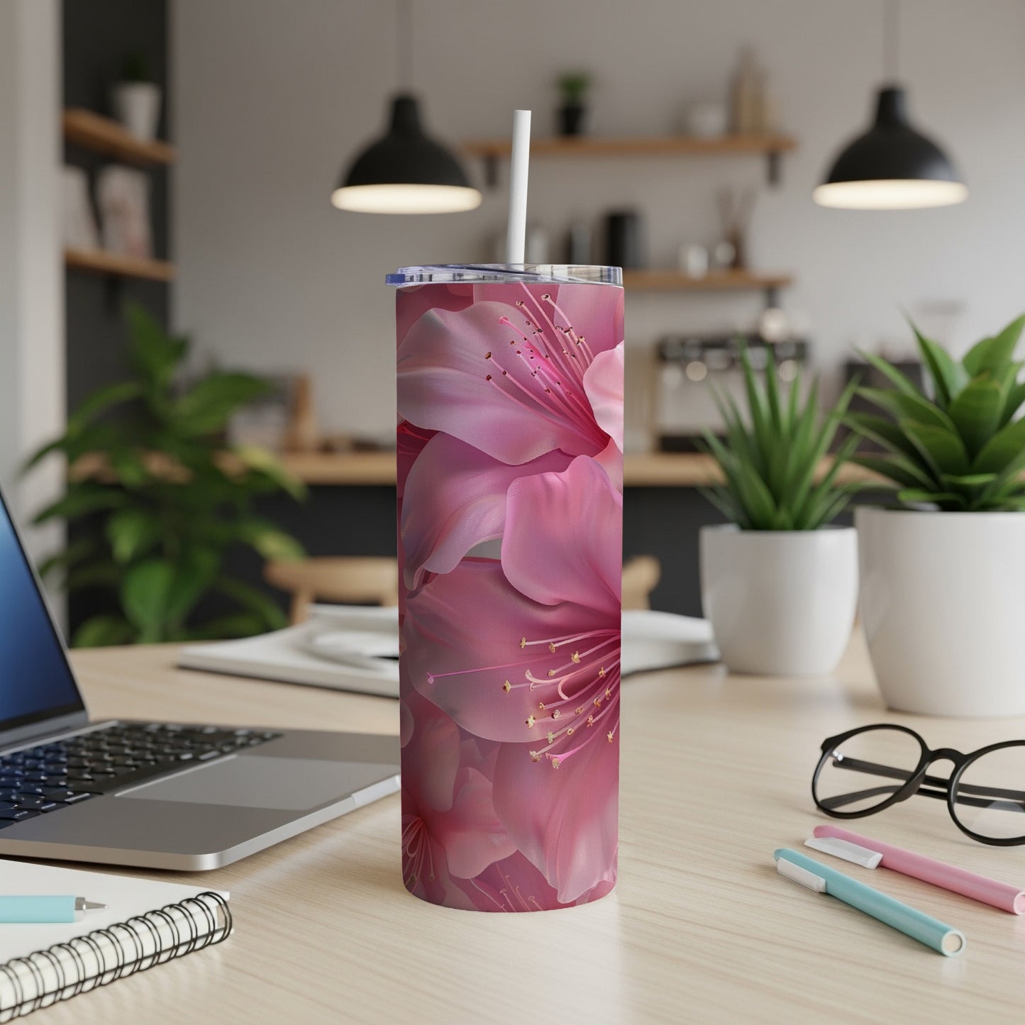 Pink floral pattern tumbler with straw on a desk.