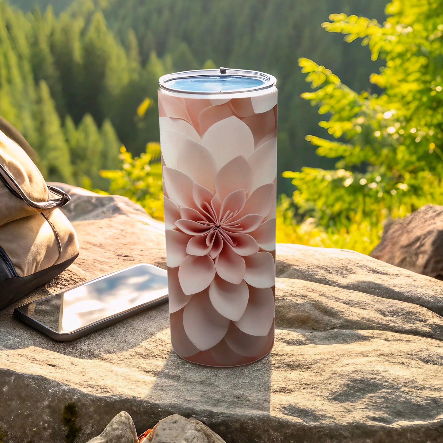 Floral pattern tumbler on rock with smartphone and backpack outdoors.