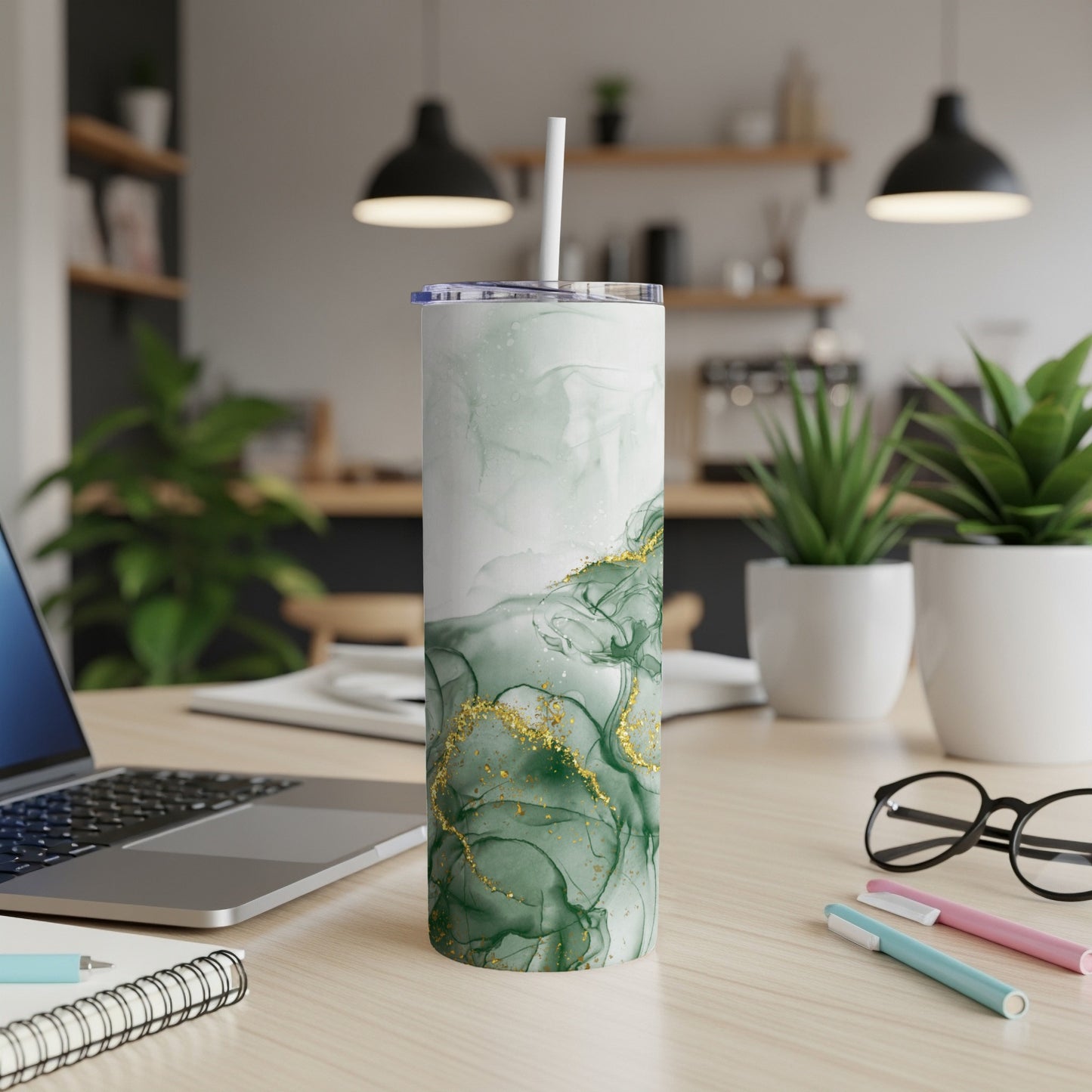 Green marble tumbler with gold accents on a desk.