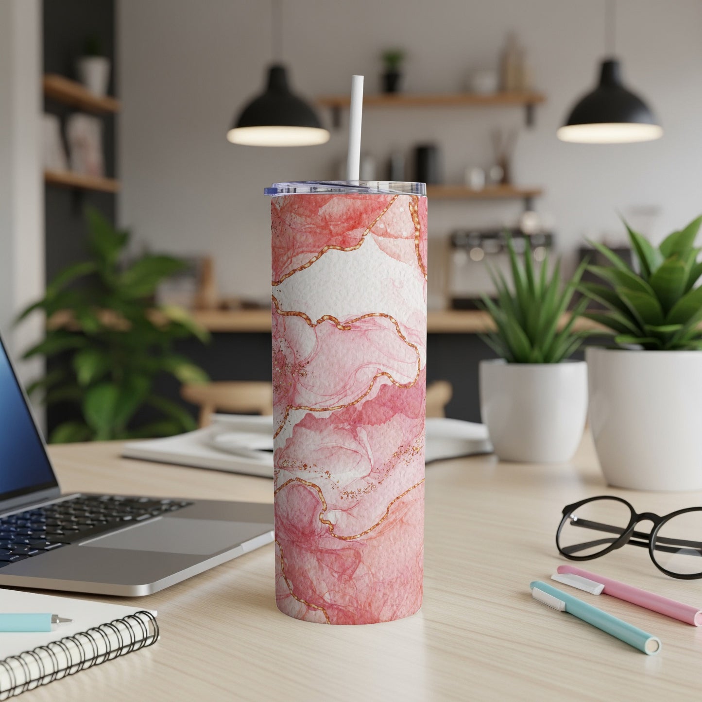 Pink marble tumbler with gold accents on a desk.