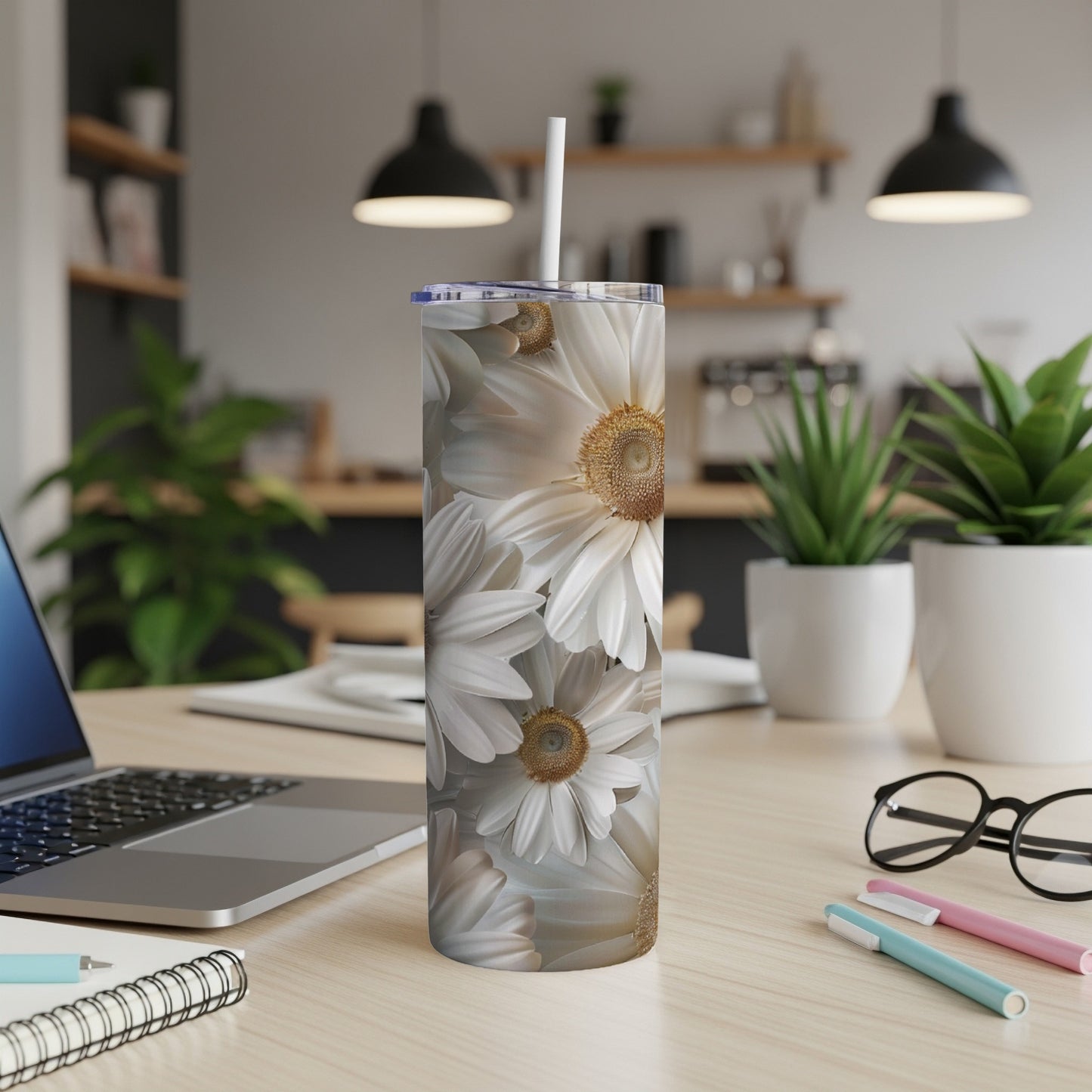 White and yellow daisies covering a white skinny tumbler with a straw.