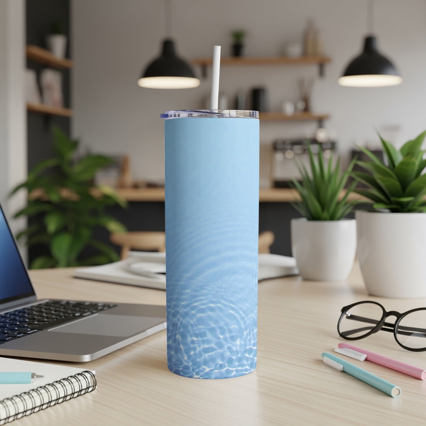 Light blue tumbler with water ripple pattern and straw on a desk.