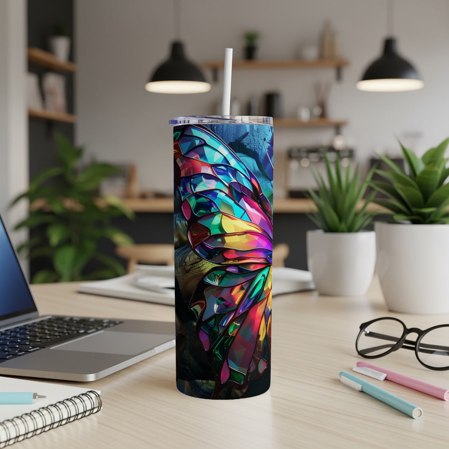 Tall tumbler with stained glass butterfly design on a desk.