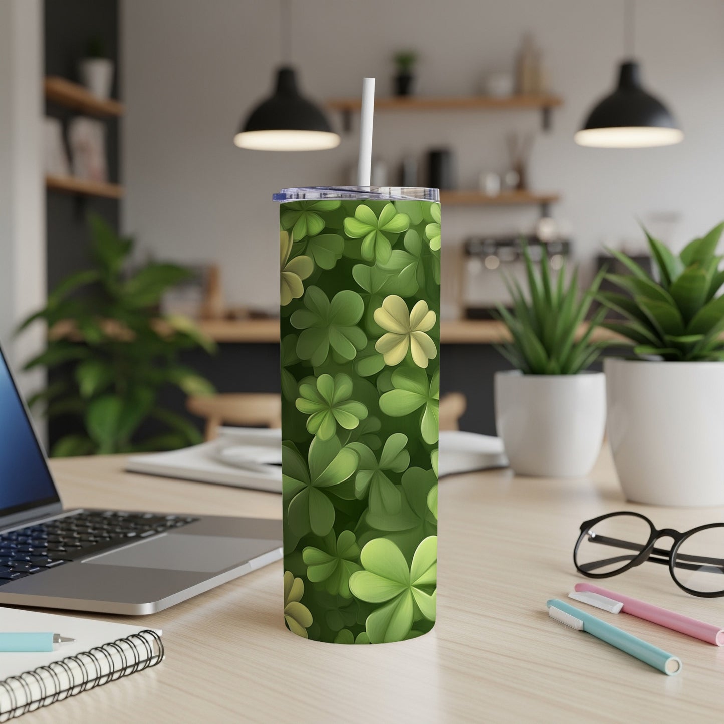 Green clover pattern insulated tumbler with straw on a desk.