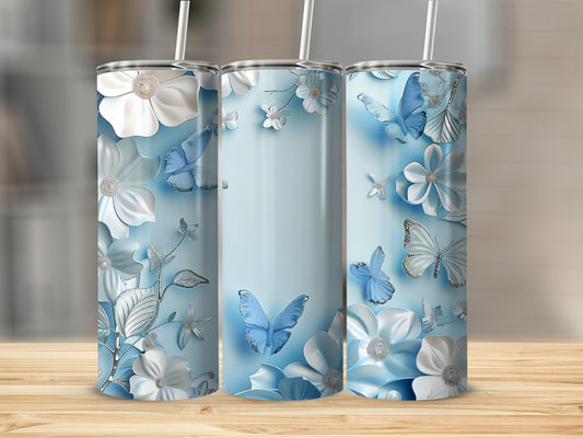 Three blue tumblers with white floral and butterfly designs on a wooden surface.