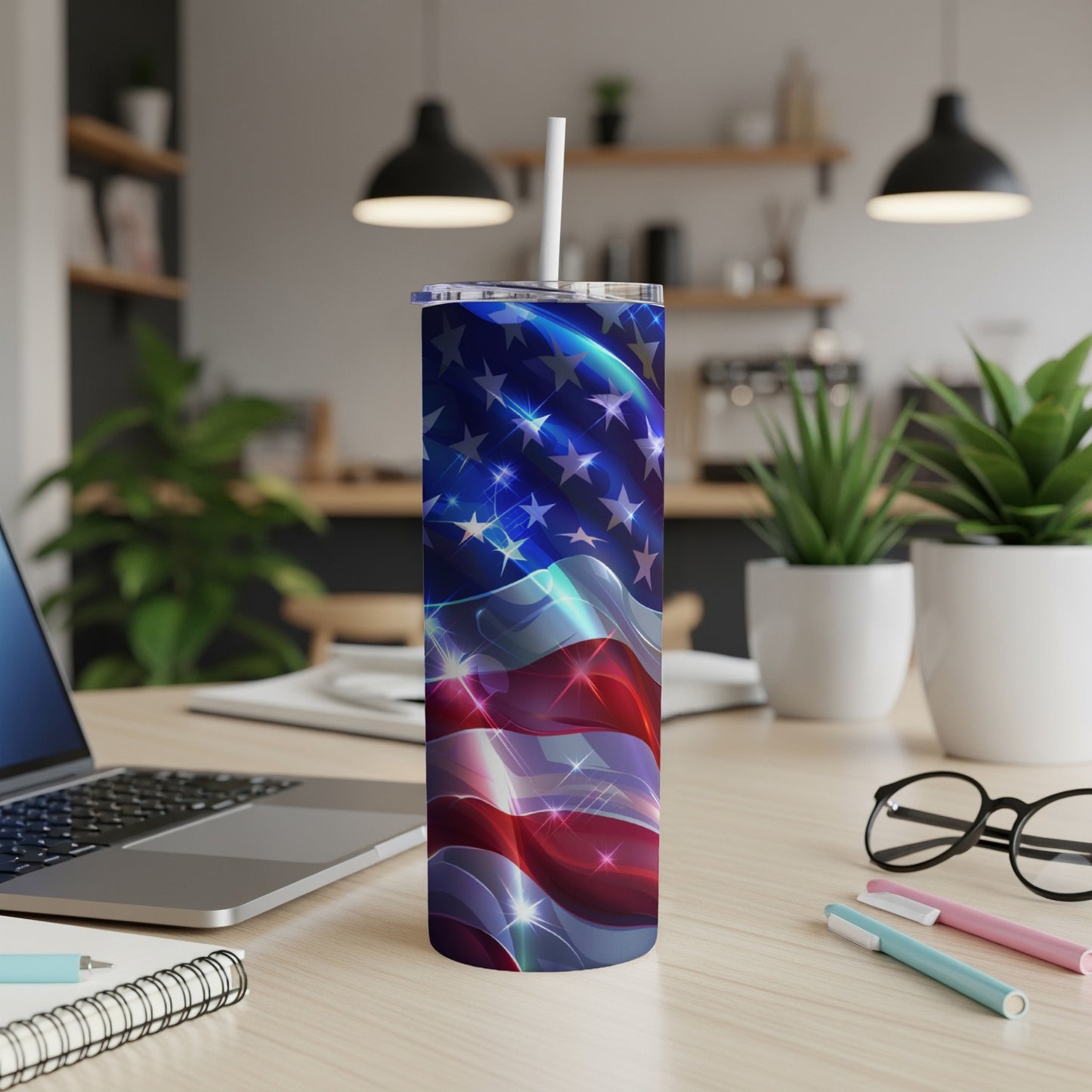 American flag tumbler with straw on a desk with a laptop and pens.