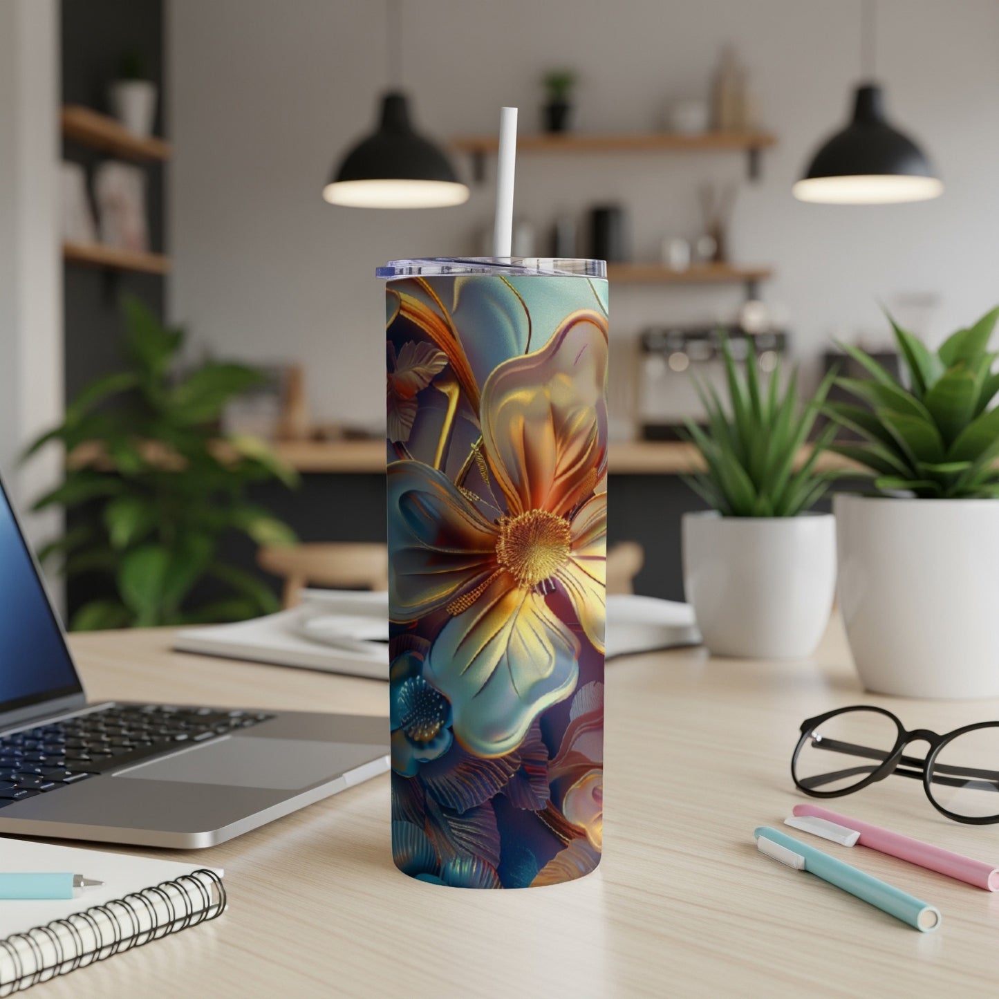 Floral pattern tumbler with straw on a desk with laptop and pens.