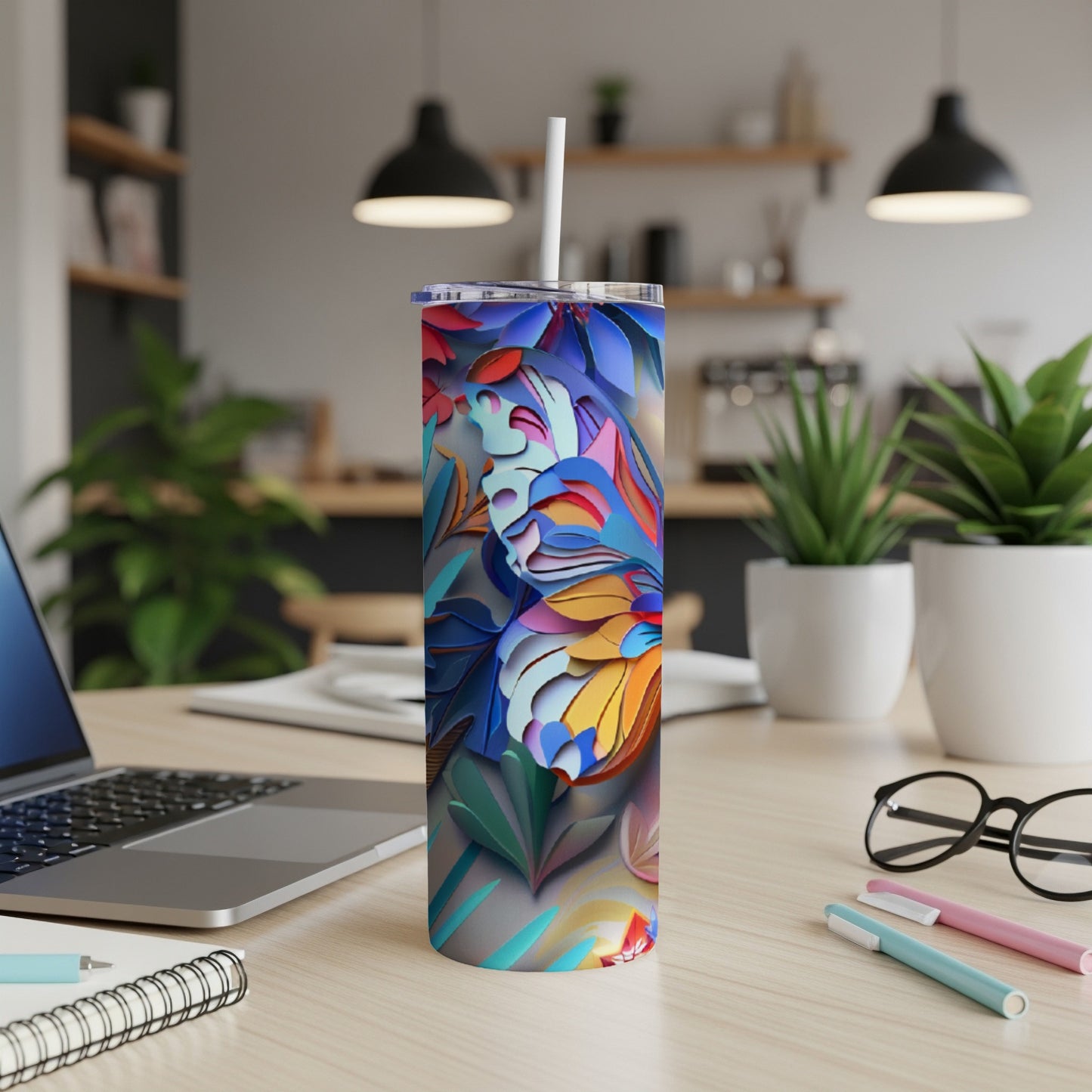 Tall tumbler with colorful floral and butterfly pattern on a desk.