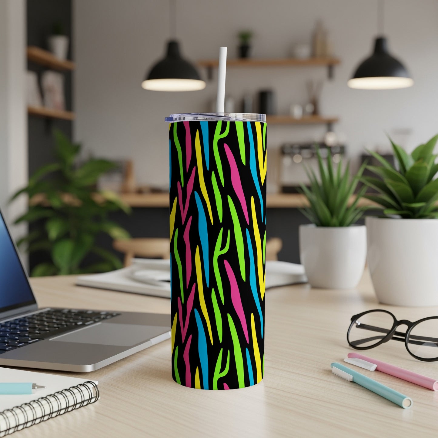 Tumbler with colorful zebra pattern and white straw on a desk.
