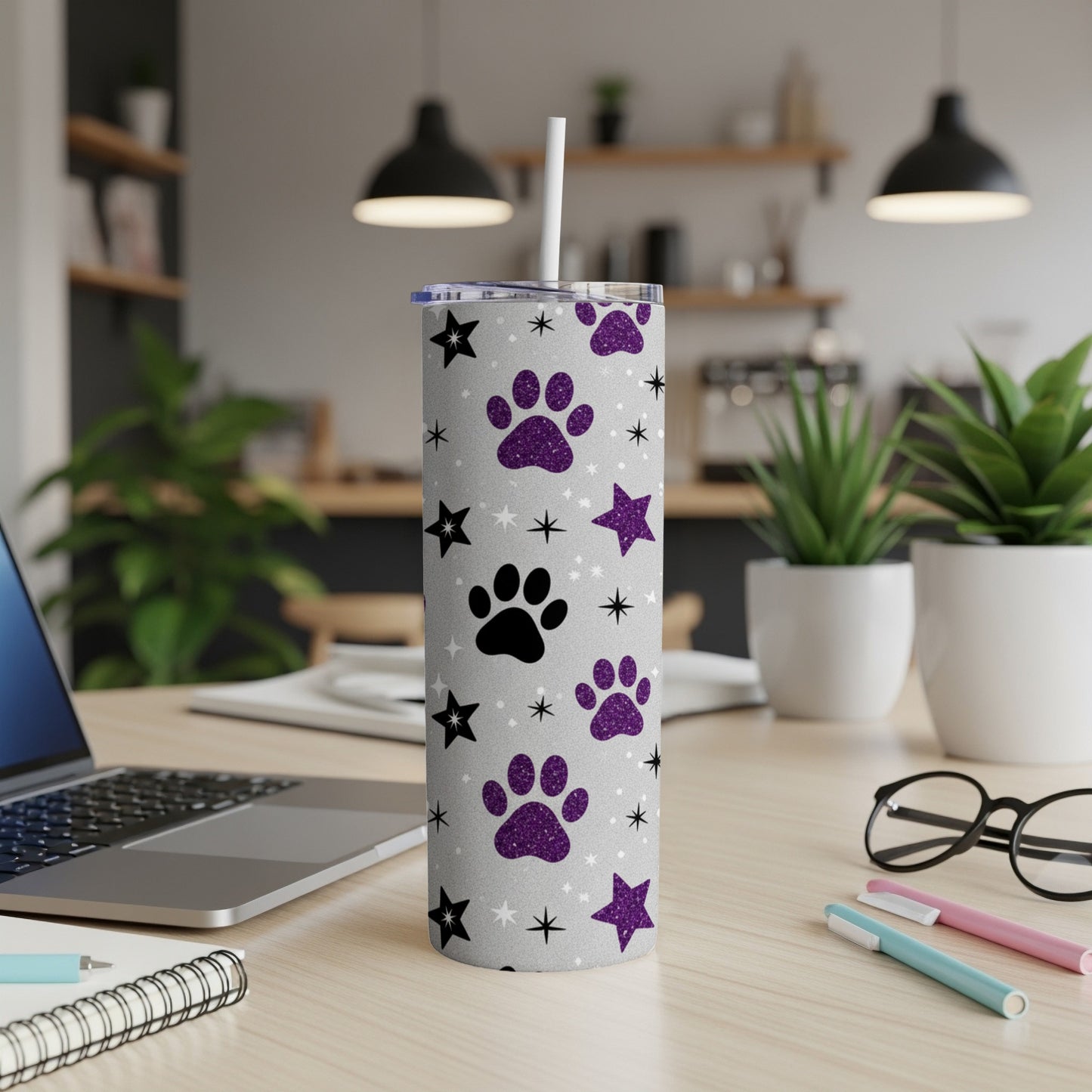 Silver tumbler with paw prints and glitter stars, with a straw.