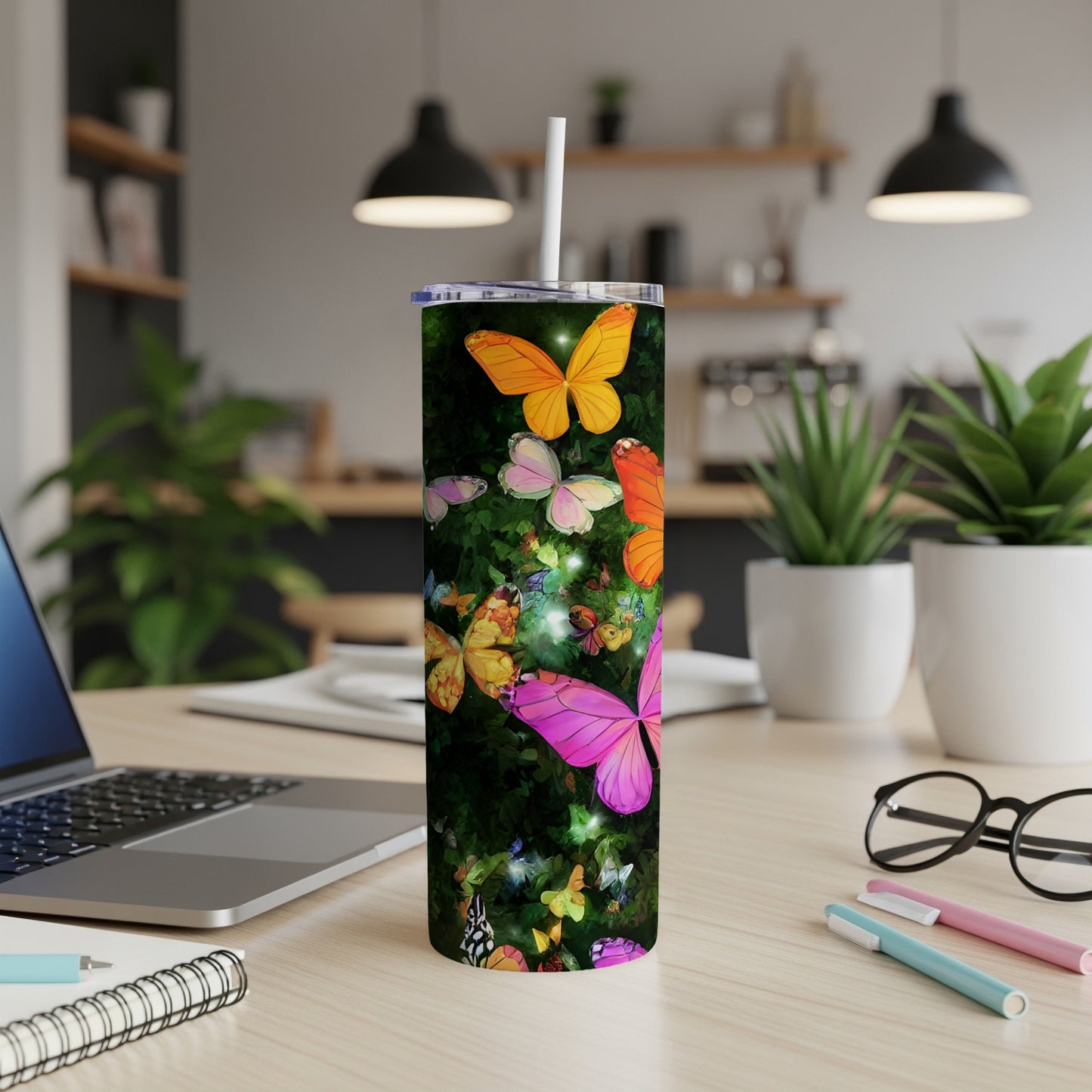 Tumbler with vibrant butterflies and floral pattern on a desk.