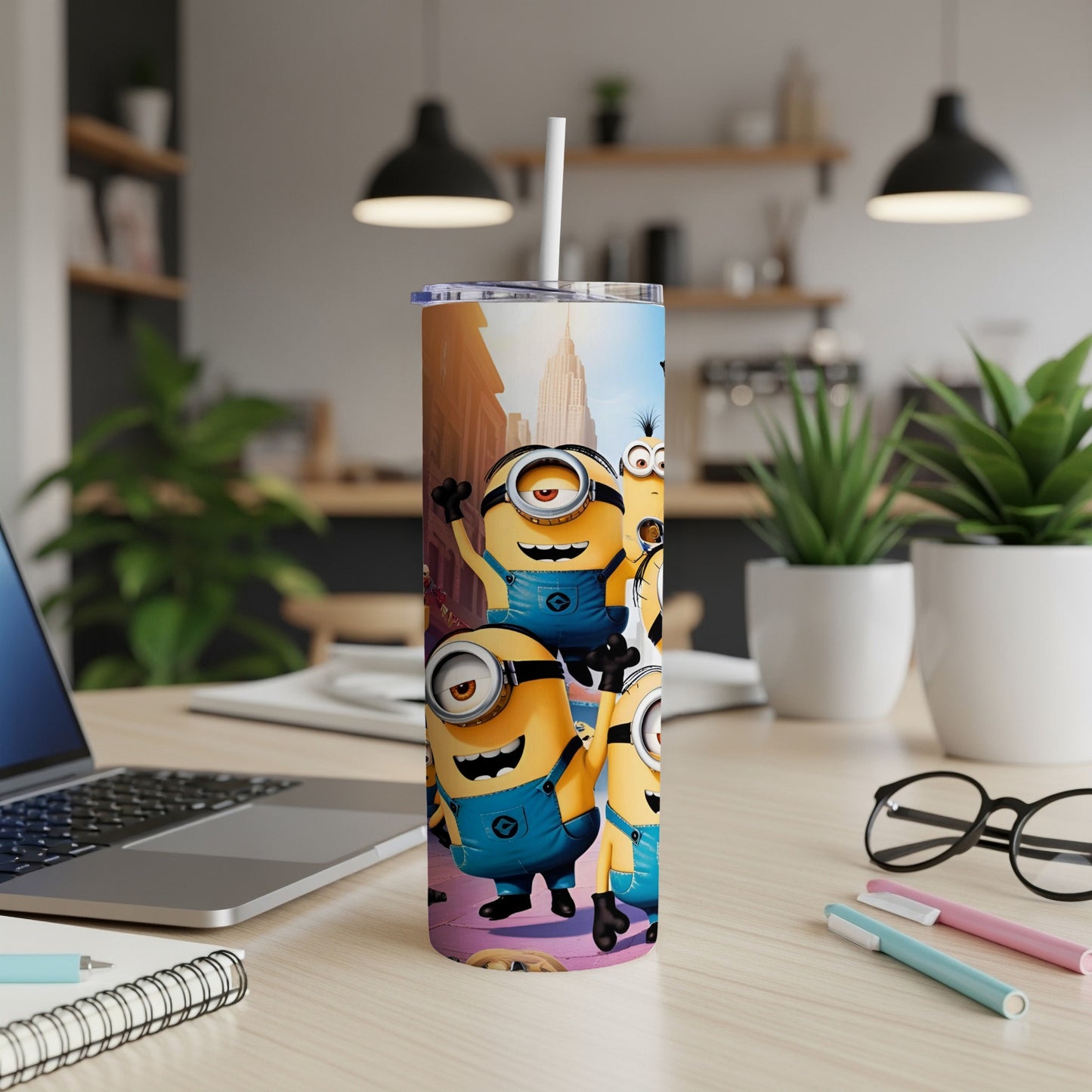 Minions characters on a cylindrical tumbler, with straw, on a desk.