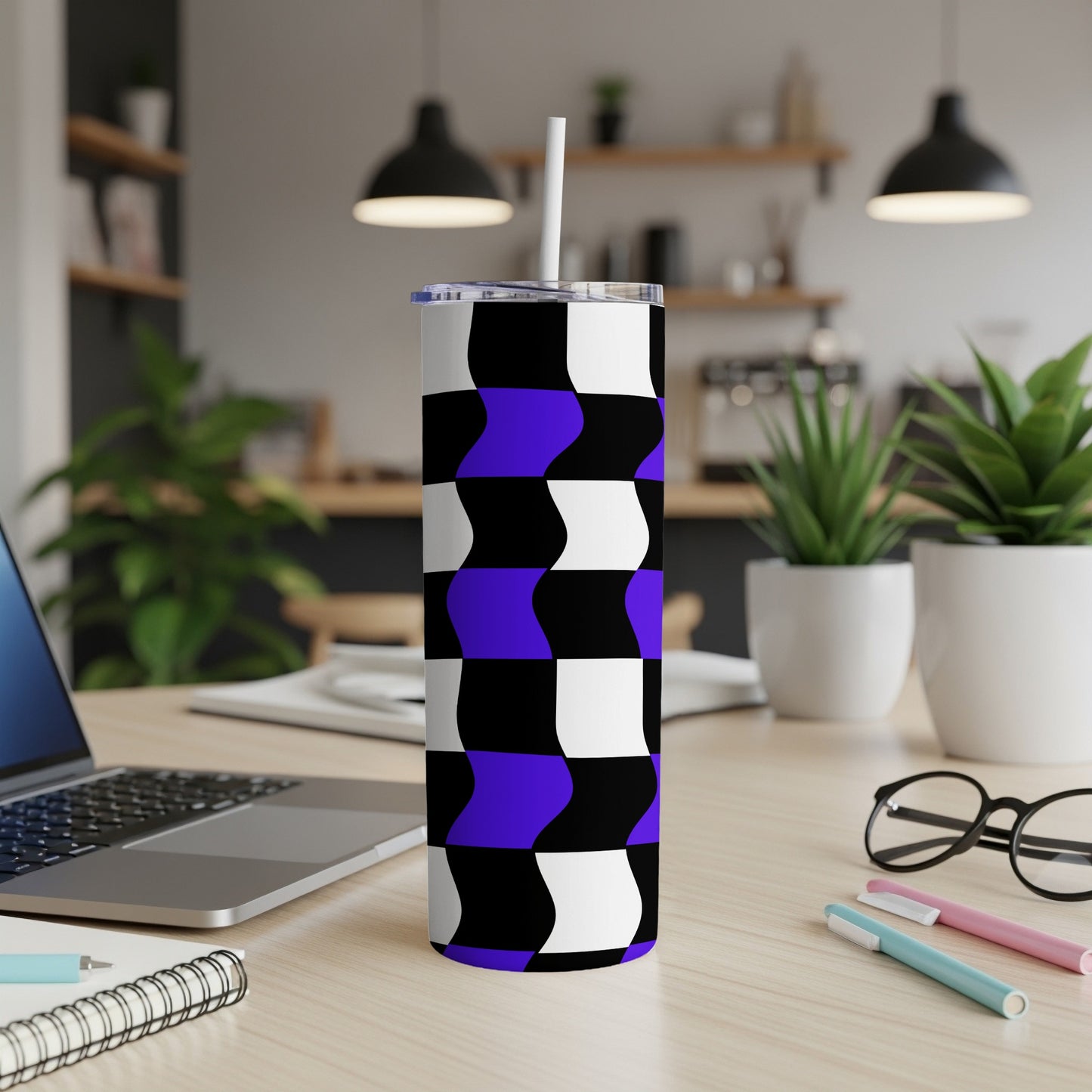 Tumbler with black, white, and purple wavy checkered pattern on a desk.