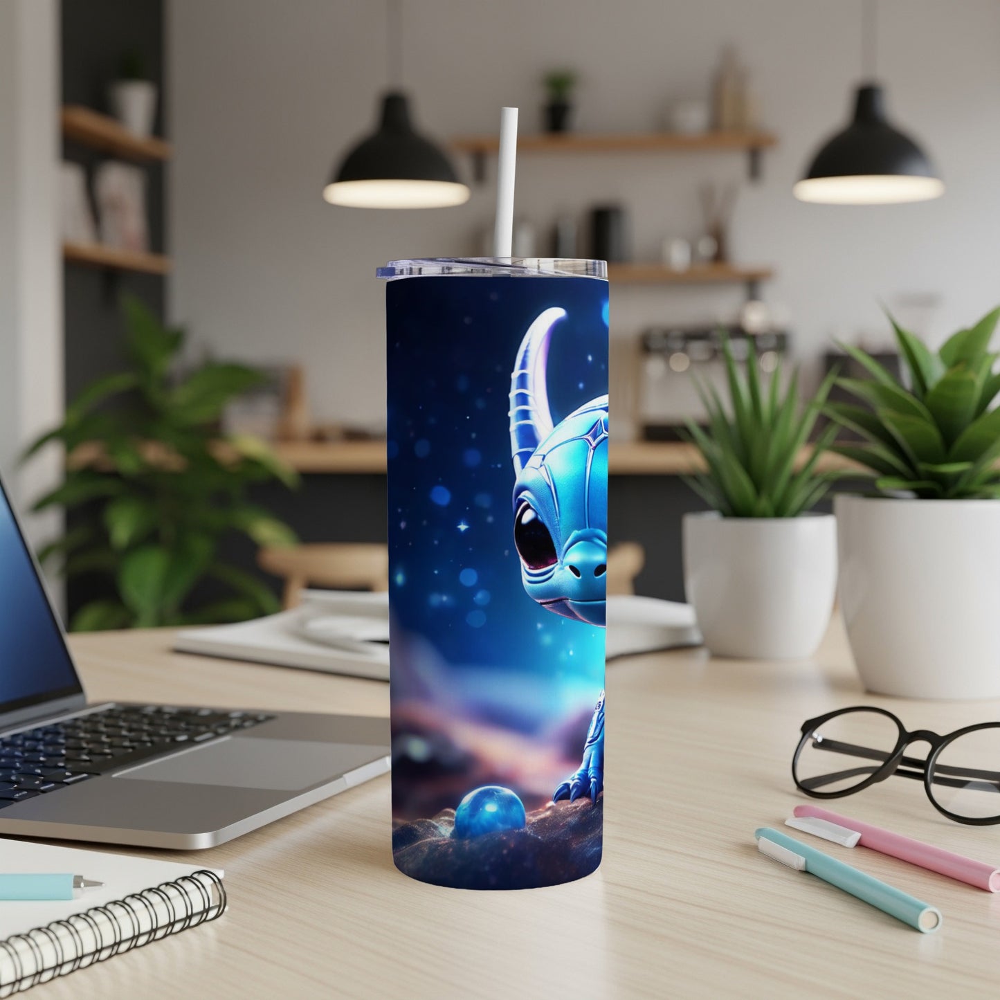 Blue dragon tumbler with straw on desk, laptop, and pens.