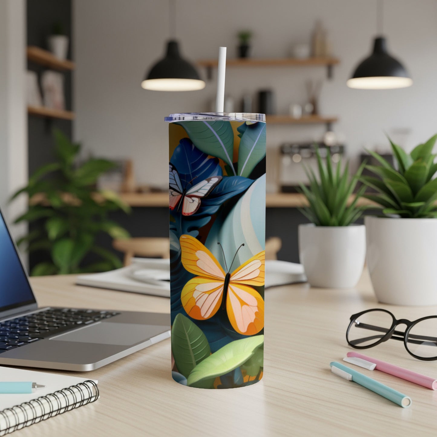 Tumbler with orange and white butterflies and tropical leaves on a desk.