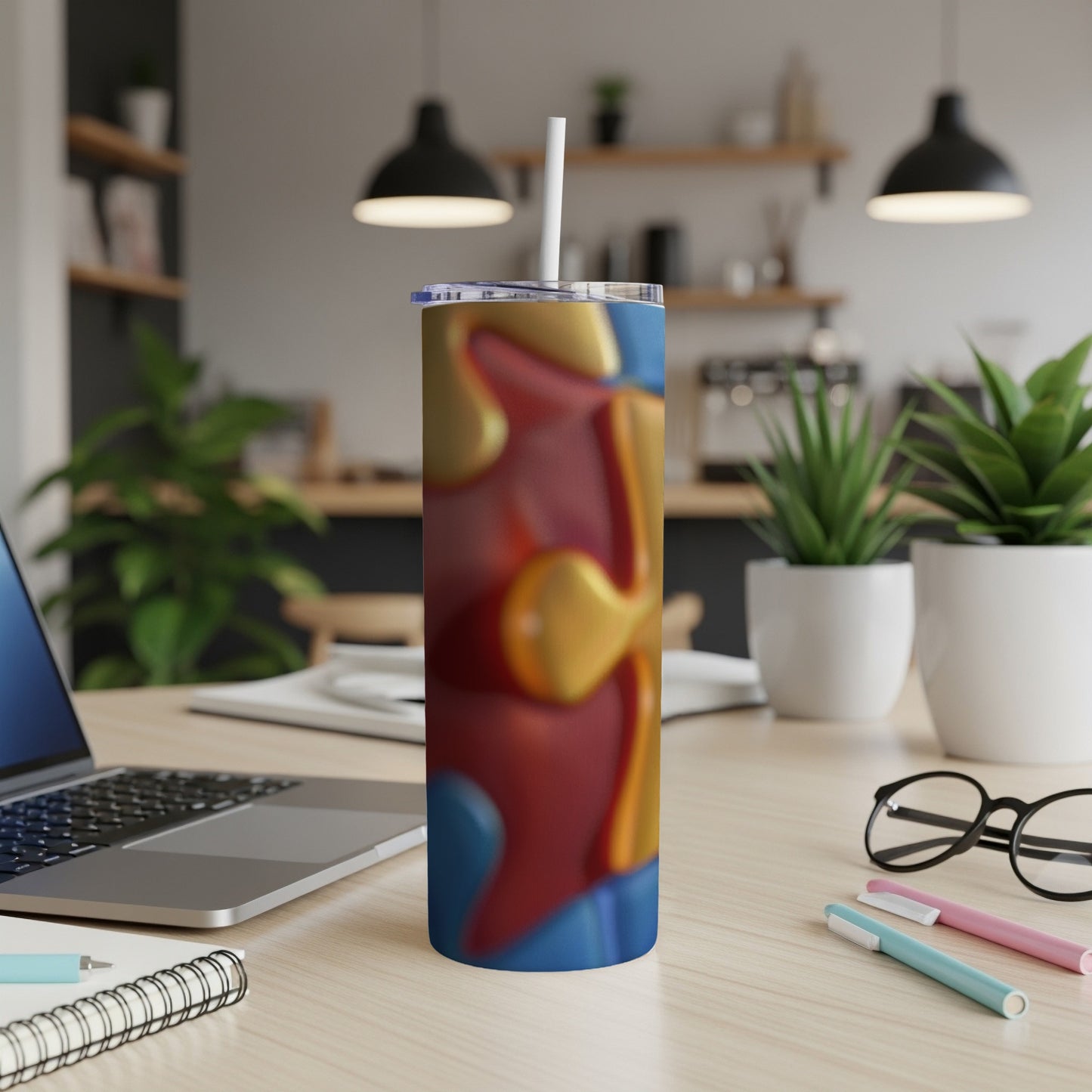 Tall blue tumbler with abstract red and yellow wavy pattern and straw.