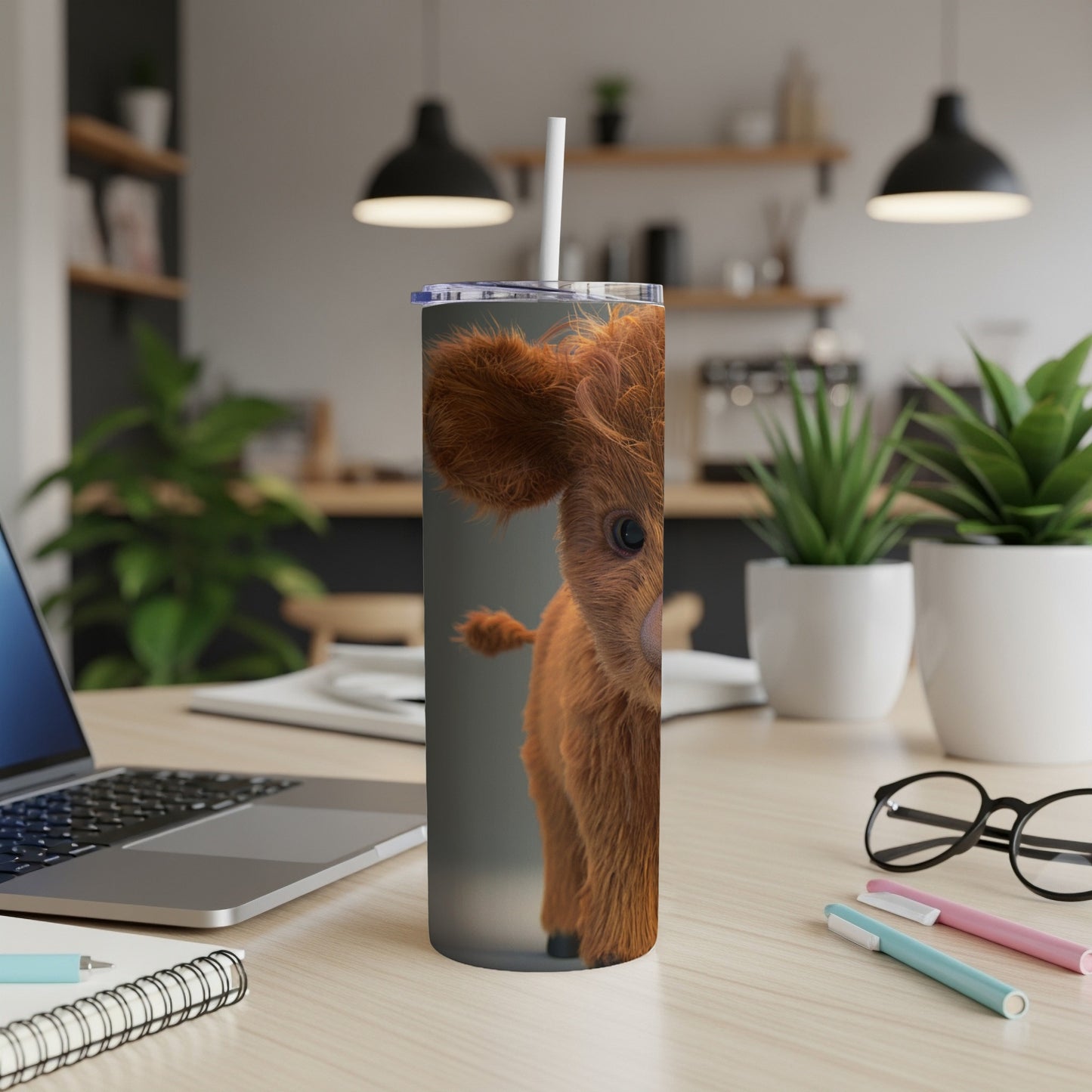 Highland cow on a tumbler with straw, on a desk.