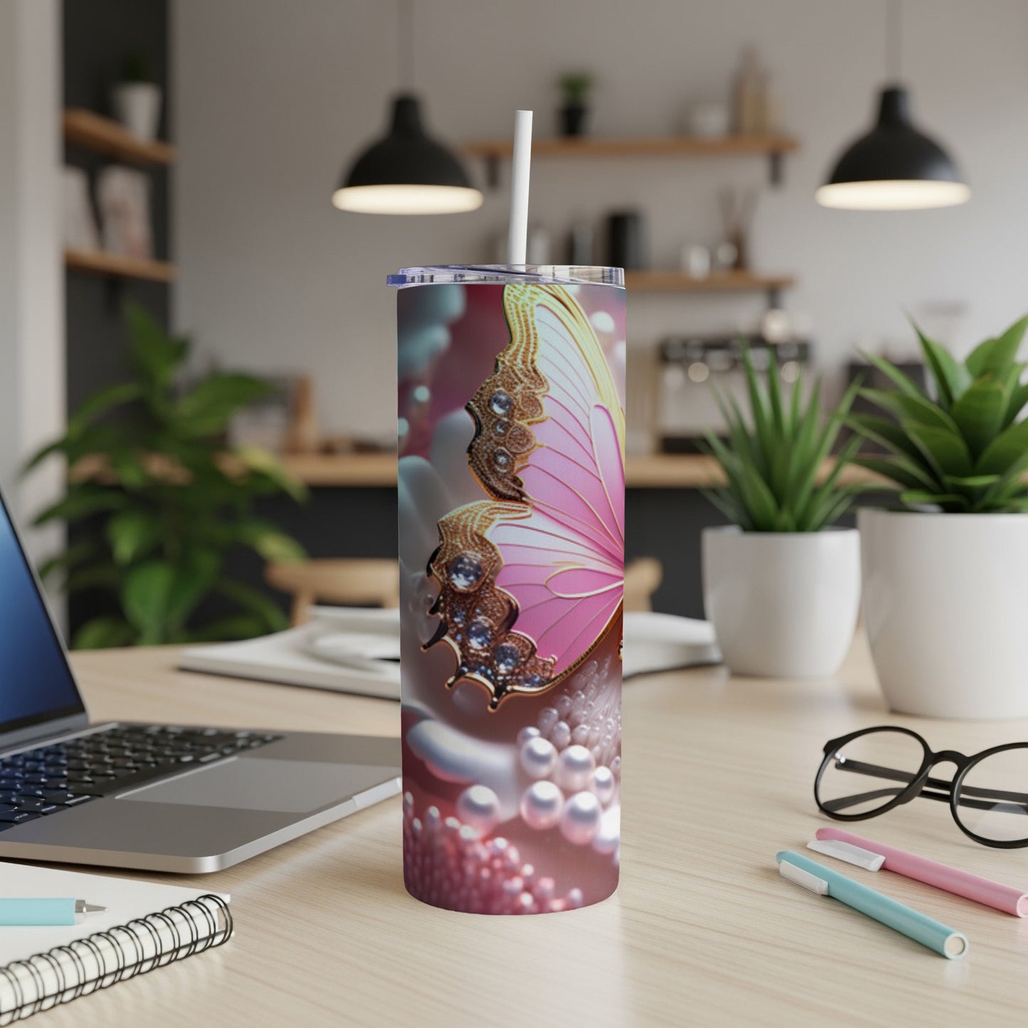 Pink butterfly tumbler with pearls and jewels on a desk.