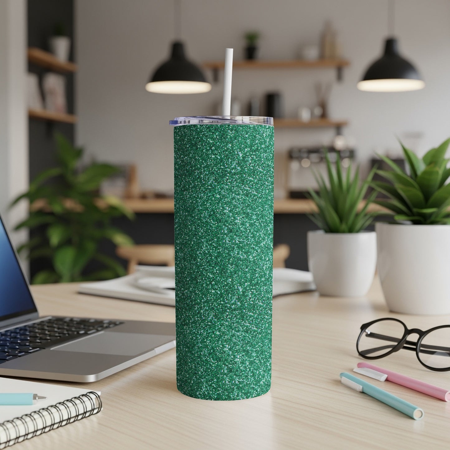 Green glitter tumbler with a straw on a desk next to a laptop.