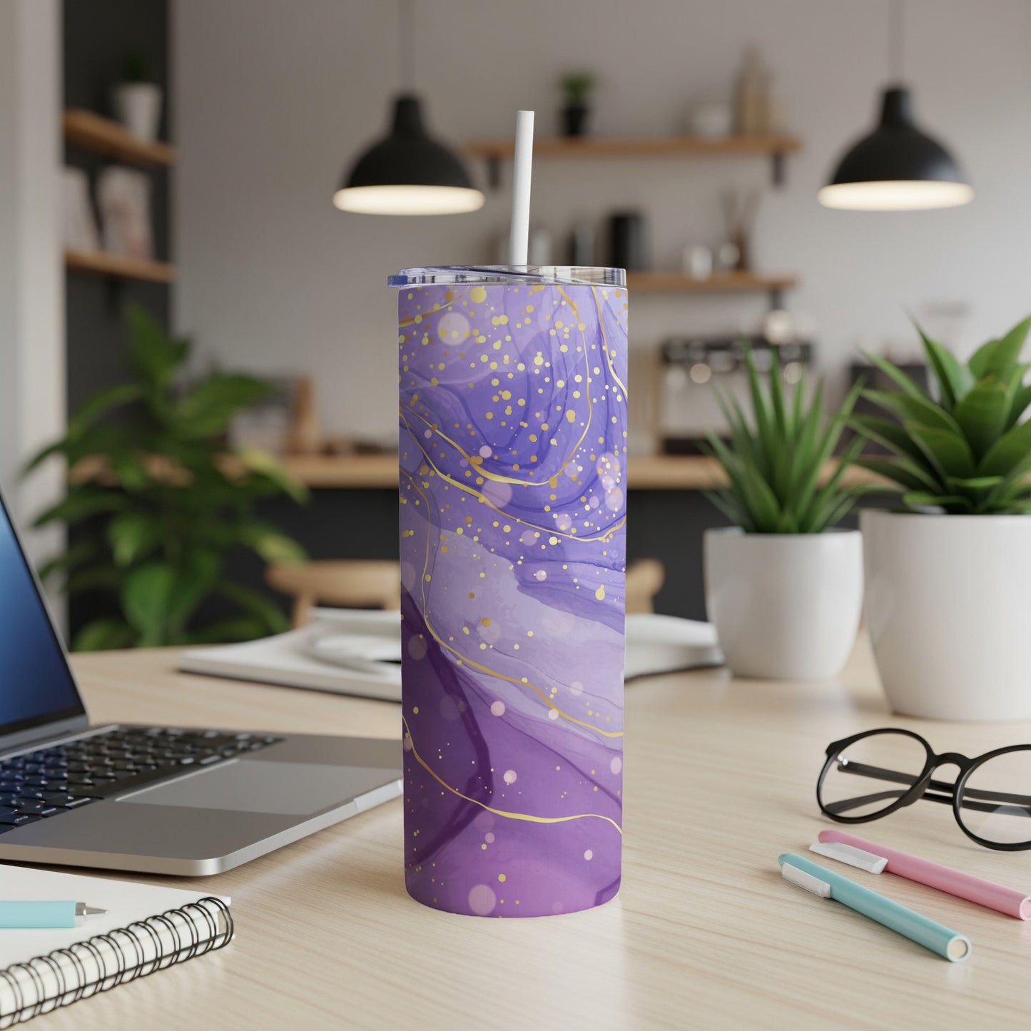 Purple and gold marbled tumbler with straw on a desk.