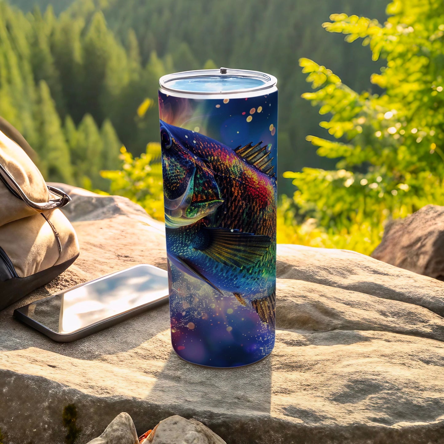 Colorful fish graphic on a tall, slim tumbler resting on rocks outdoors.