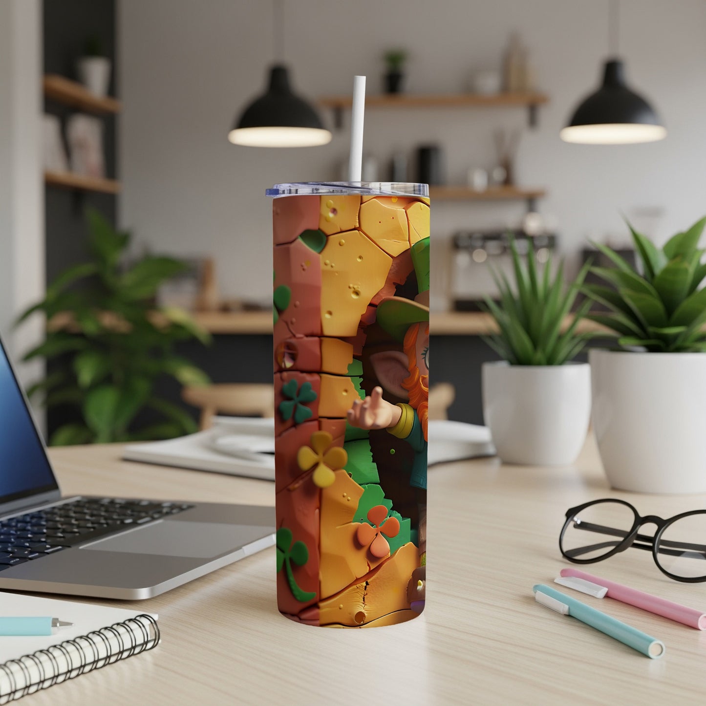 Leprechaun illustration on a patterned tumbler with a straw, on a desk.