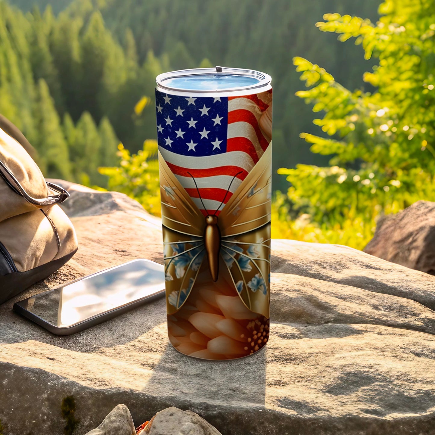 Tumbler with American flag wings and butterfly design on rocky, outdoor background.