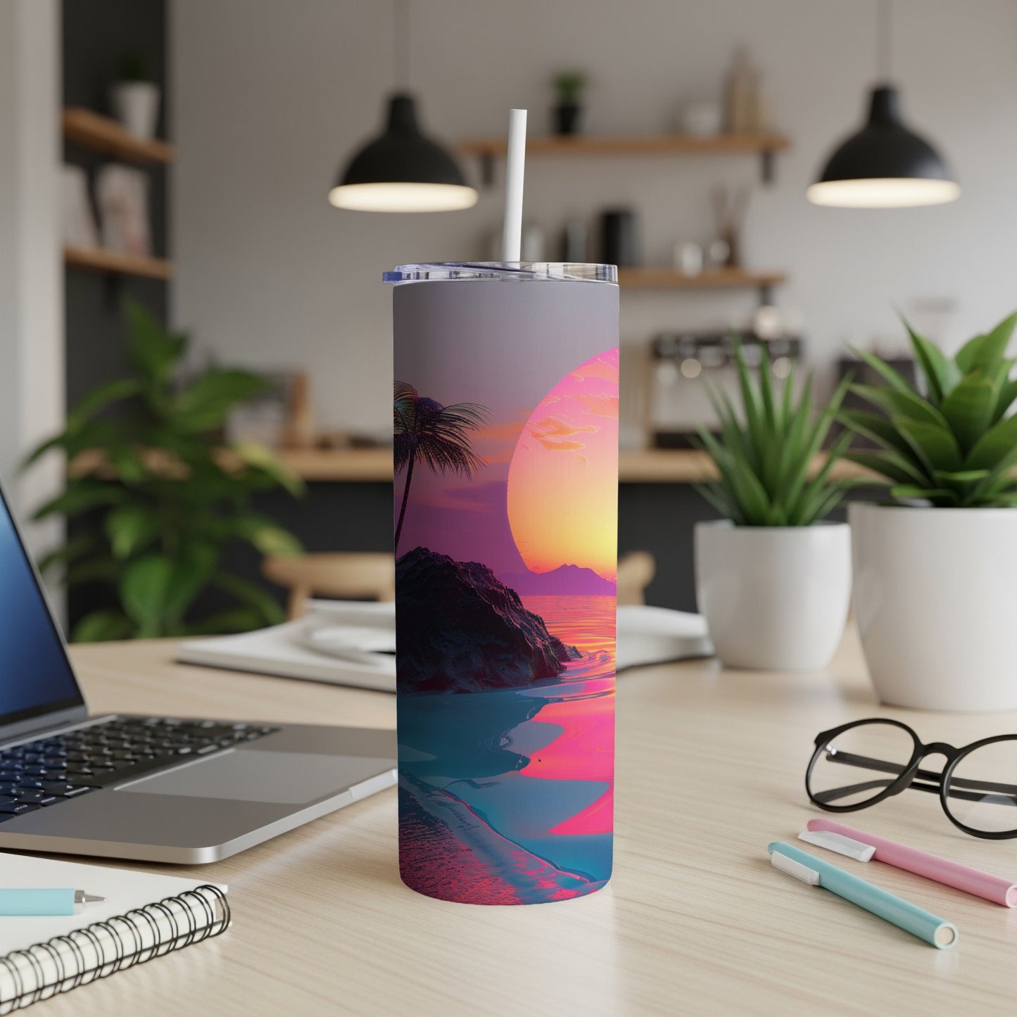 Sunset beach scene on a tumbler with a straw, displayed on a desk.